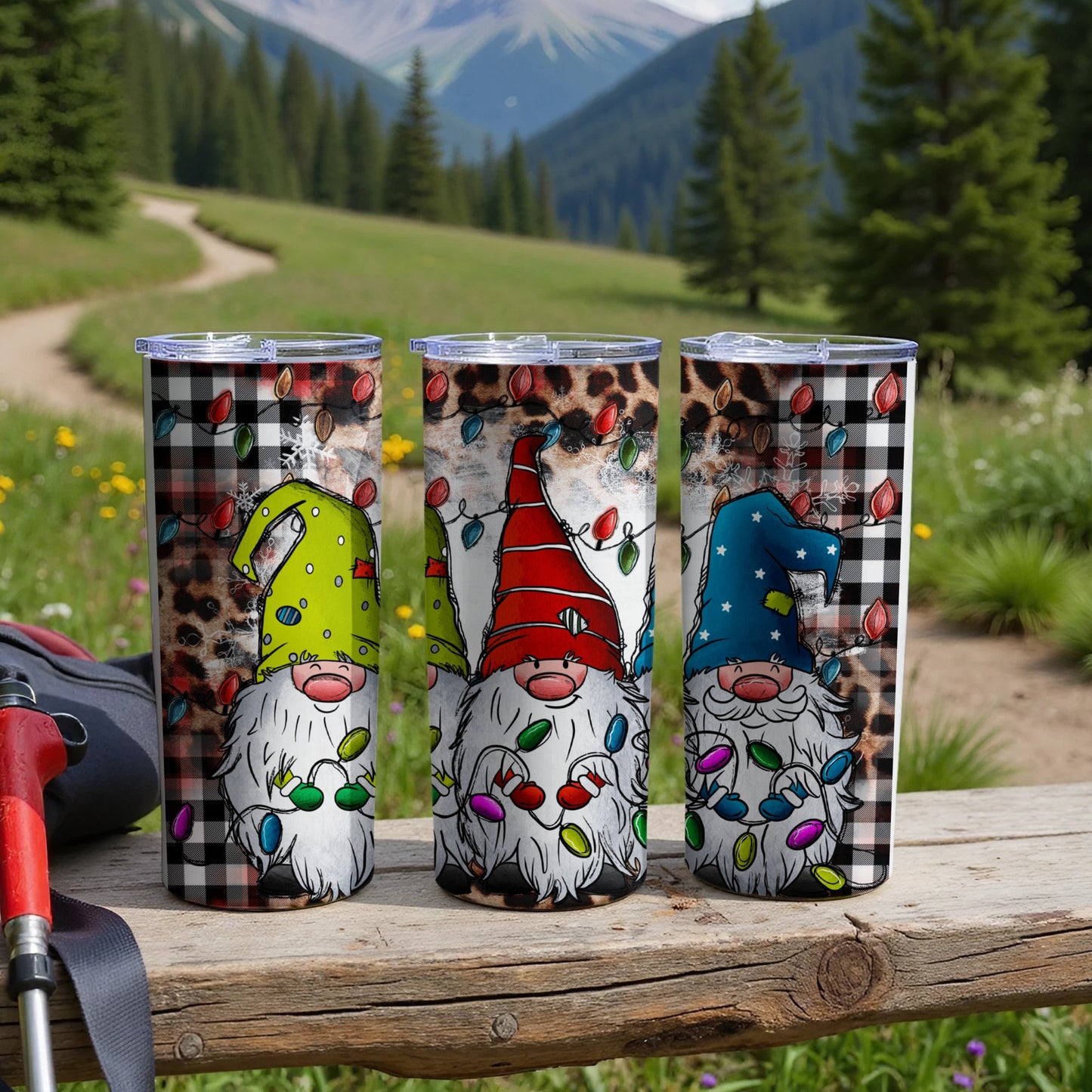 Three tumblers with gnomes and Christmas lights on a wooden surface.