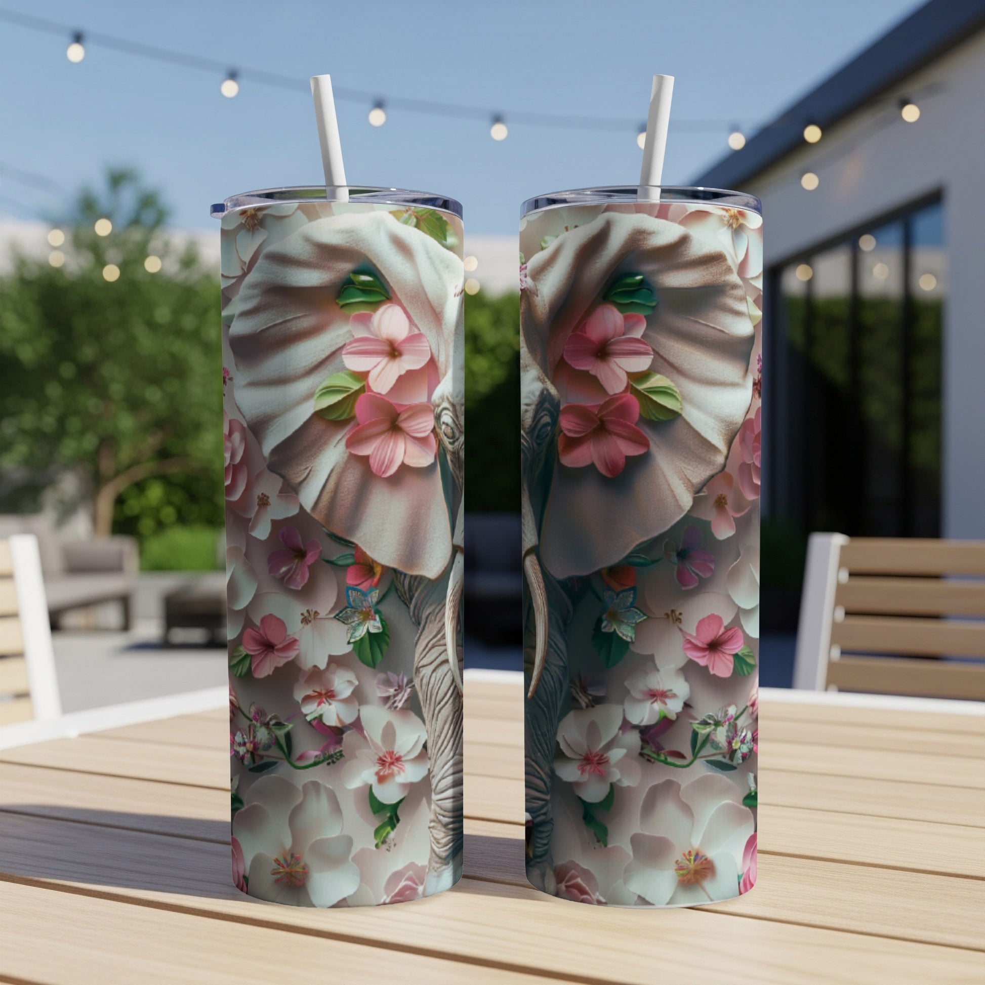 Floral elephant design on two tall tumblers with straws on a wooden table.