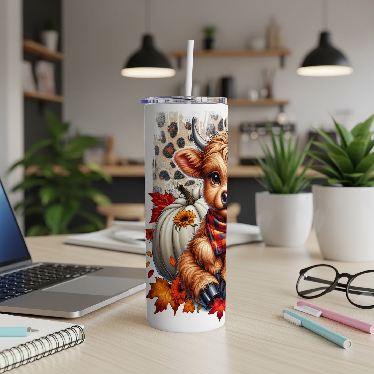 Cow and pumpkins on a tumbler with autumn leaves, placed on a desk.