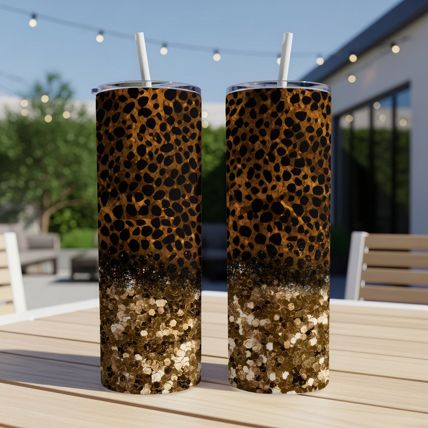 Leopard print and glitter design on two tall tumblers on an outdoor table.