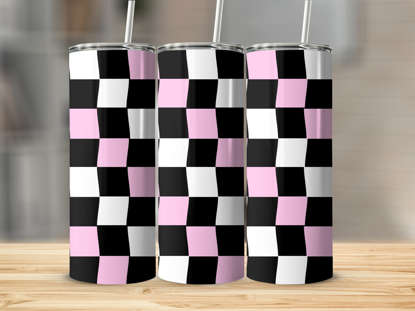 Three pink and black checkered tumblers with straws on a wooden surface.