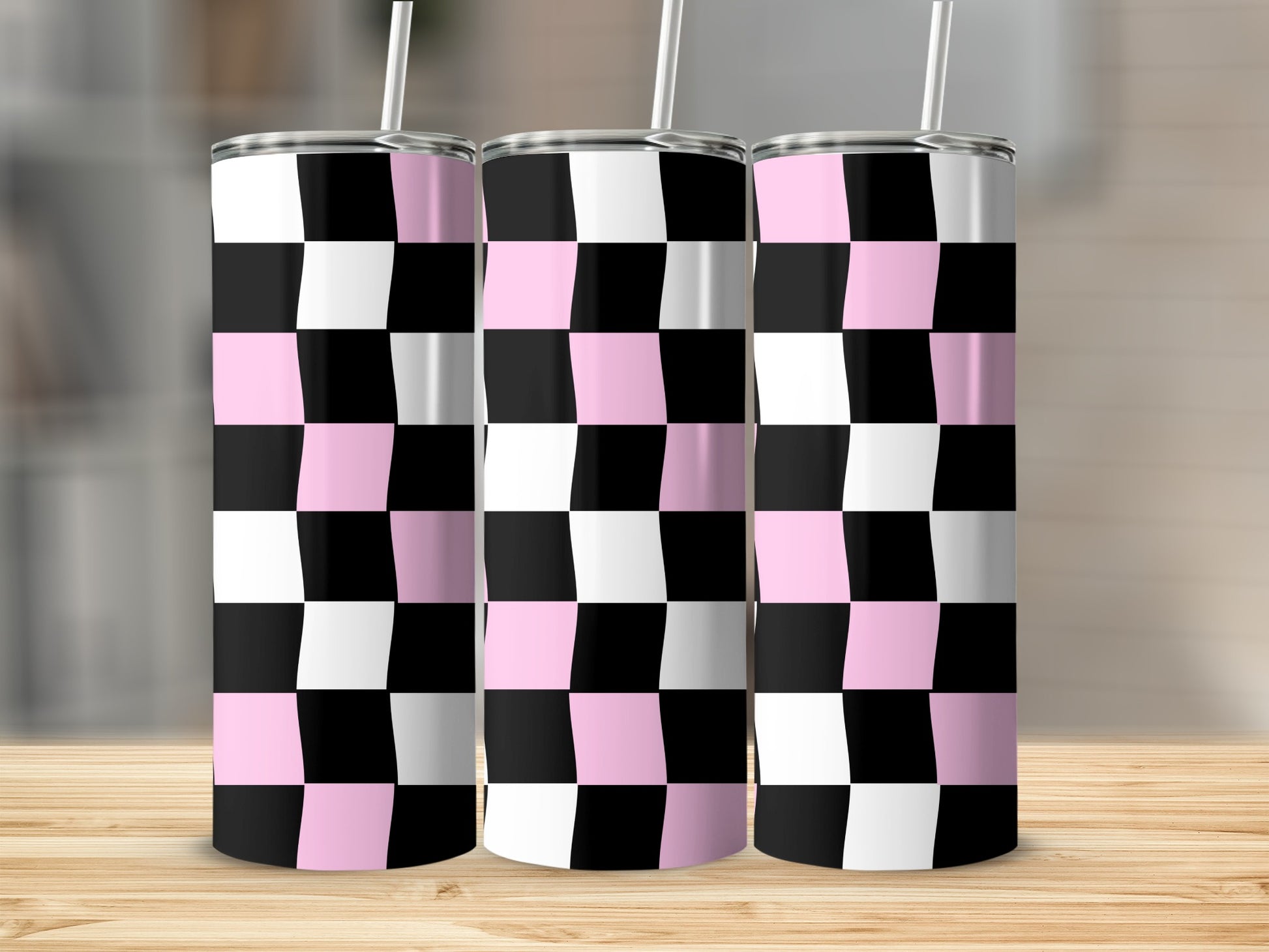 Three pink and black checkered tumblers with straws on a wooden surface.