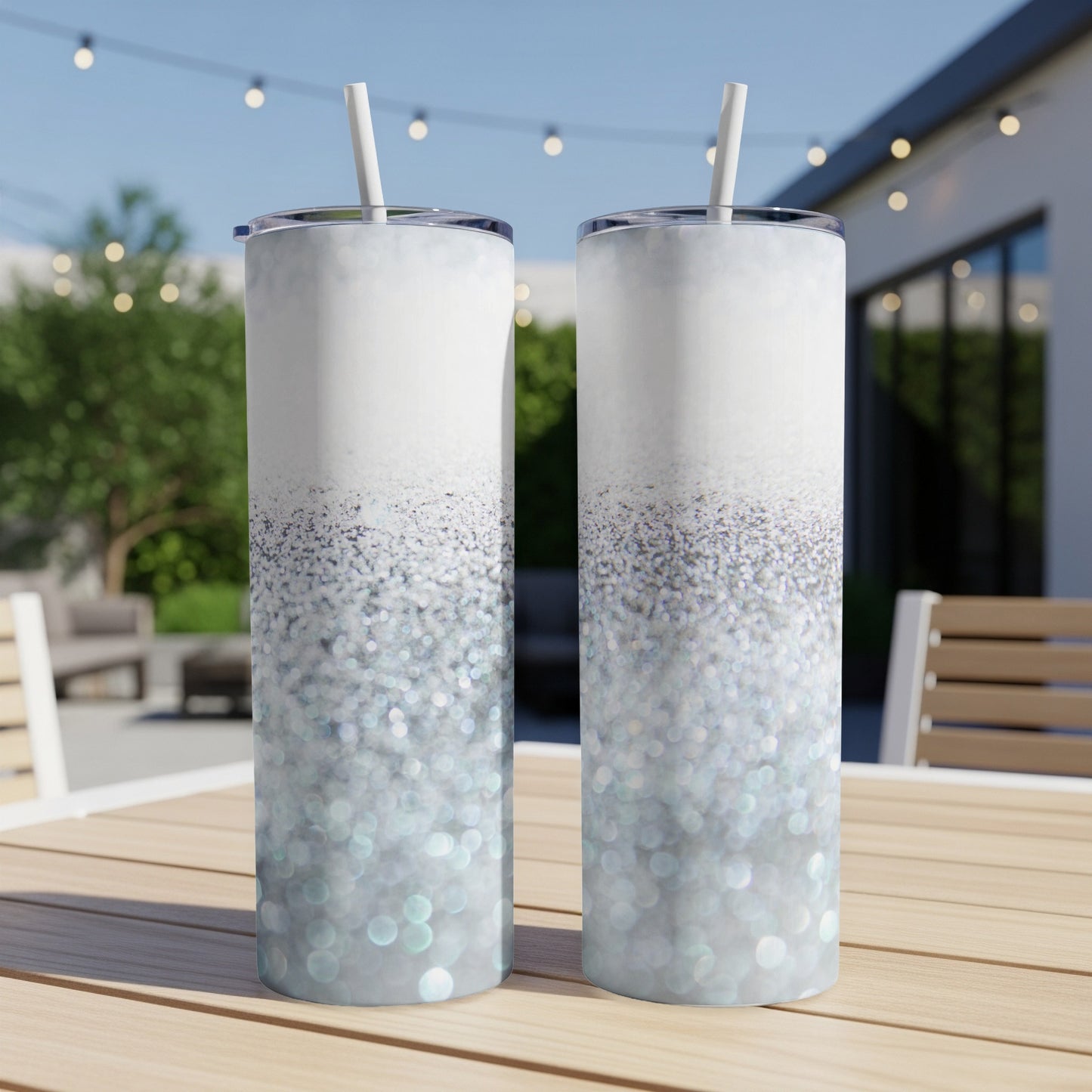 Two tall tumblers with sparkling glitter gradient, outdoors on a table.