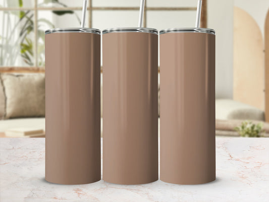 Three plain brown tumblers with straws stand on a marble countertop.