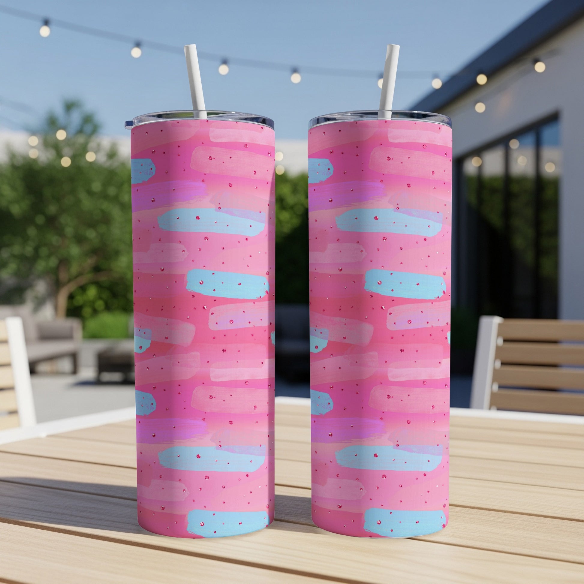 Two pink tumblers with abstract blue and pink brushstrokes and glitter.