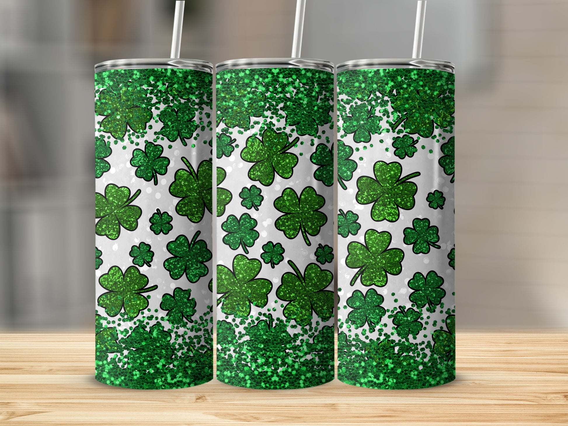 Three green glitter shamrock print tumblers with white straws.