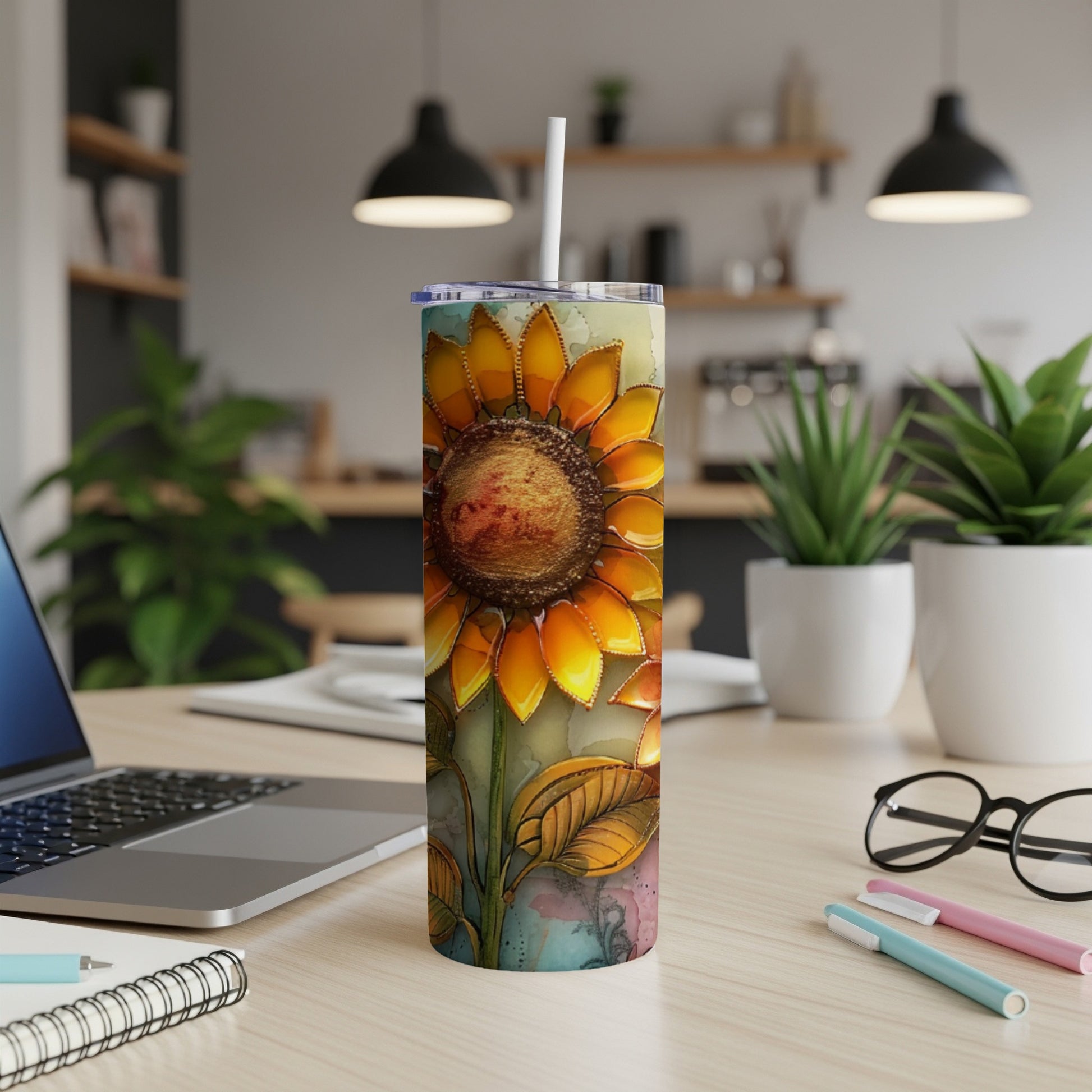 Tall tumbler with a watercolor sunflower design, on a desk.