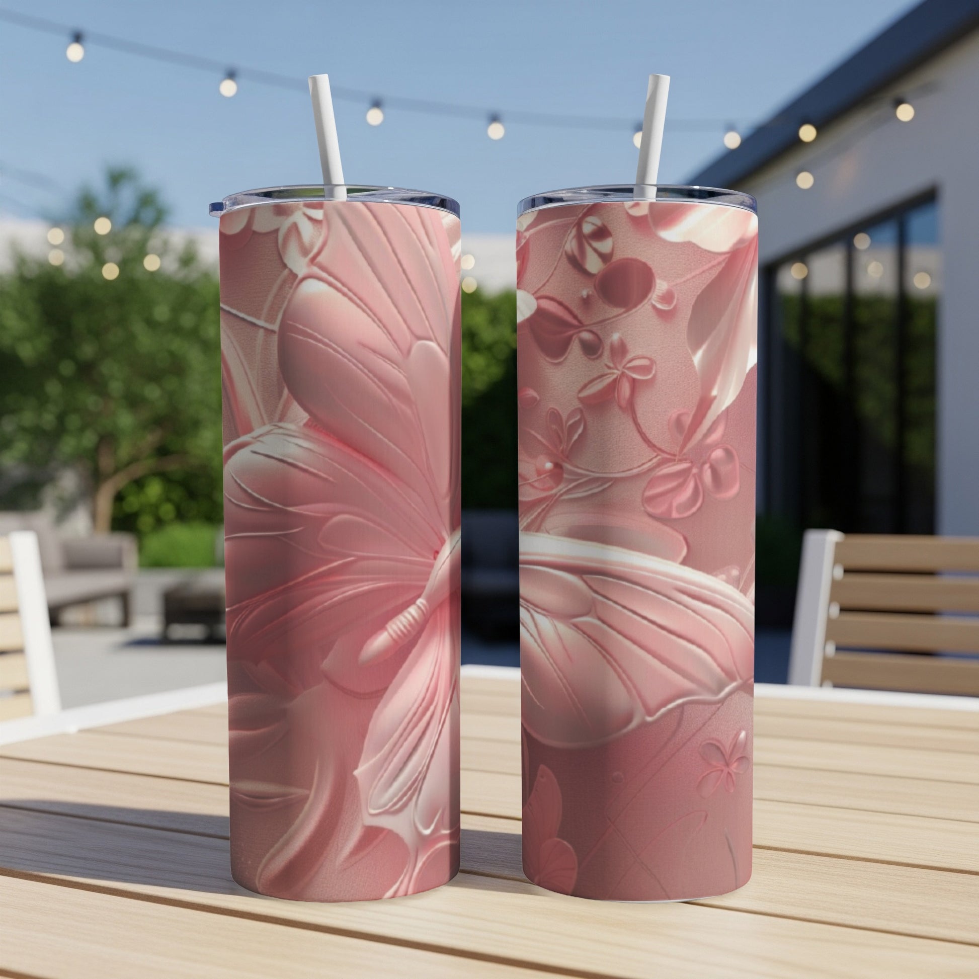 Two pink floral tumblers with butterfly accents on a wooden table.