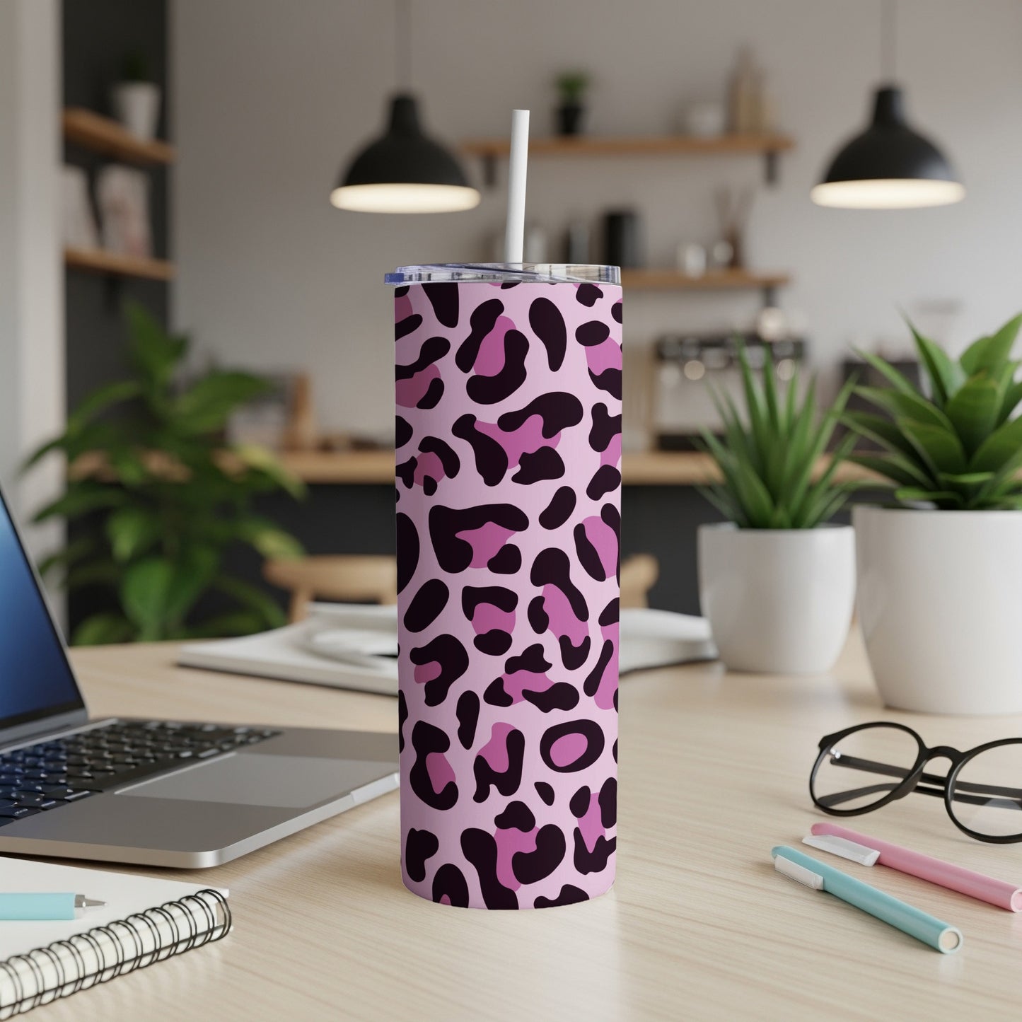 Pink and black leopard print tumbler with straw on a desk.