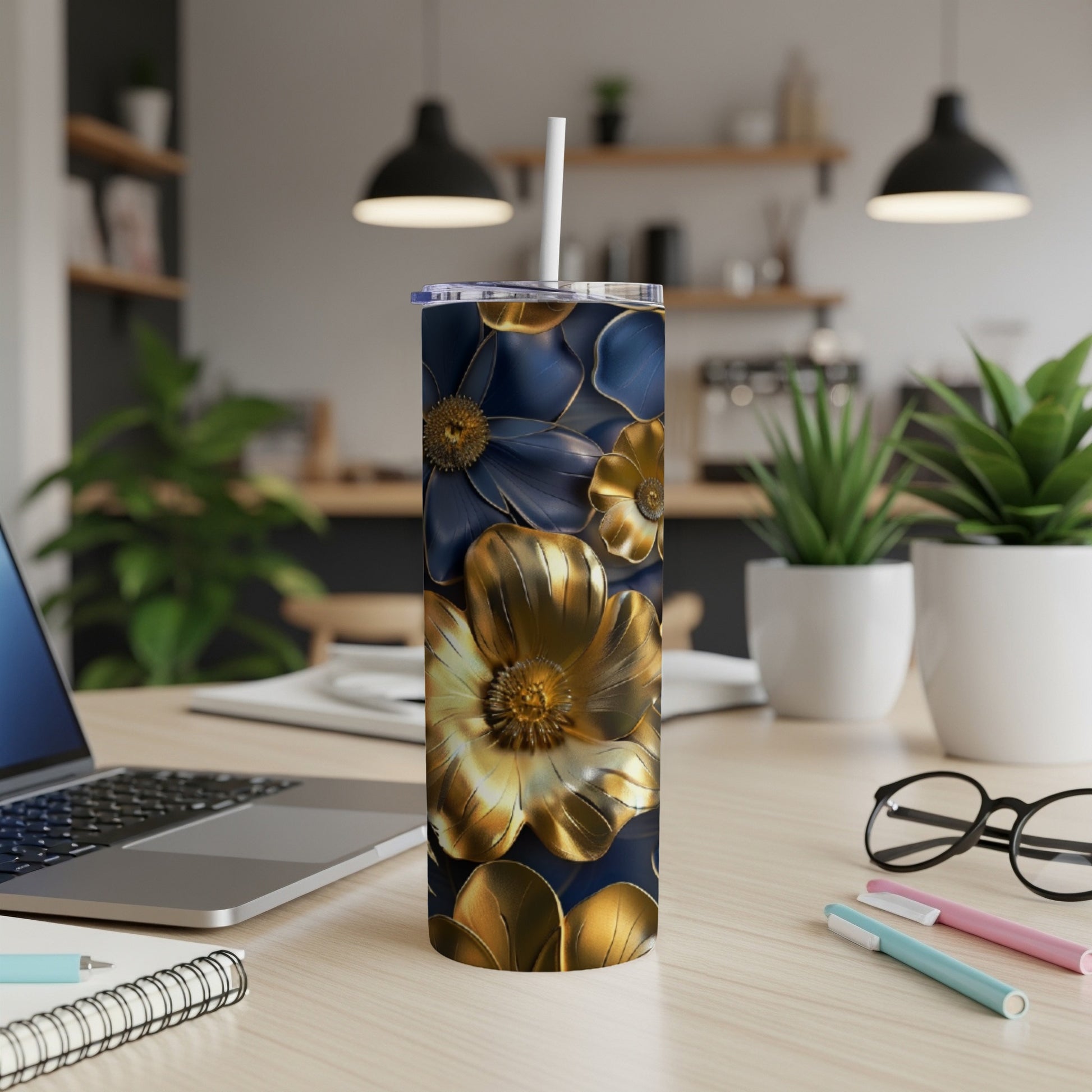 Blue and gold floral patterned tumbler with straw on a desk.