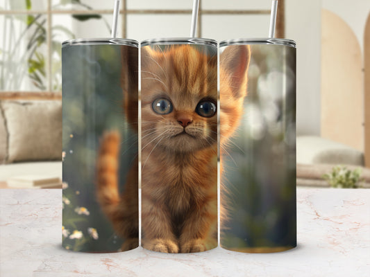 Orange tabby kitten with large blue eyes on a tumbler cup.