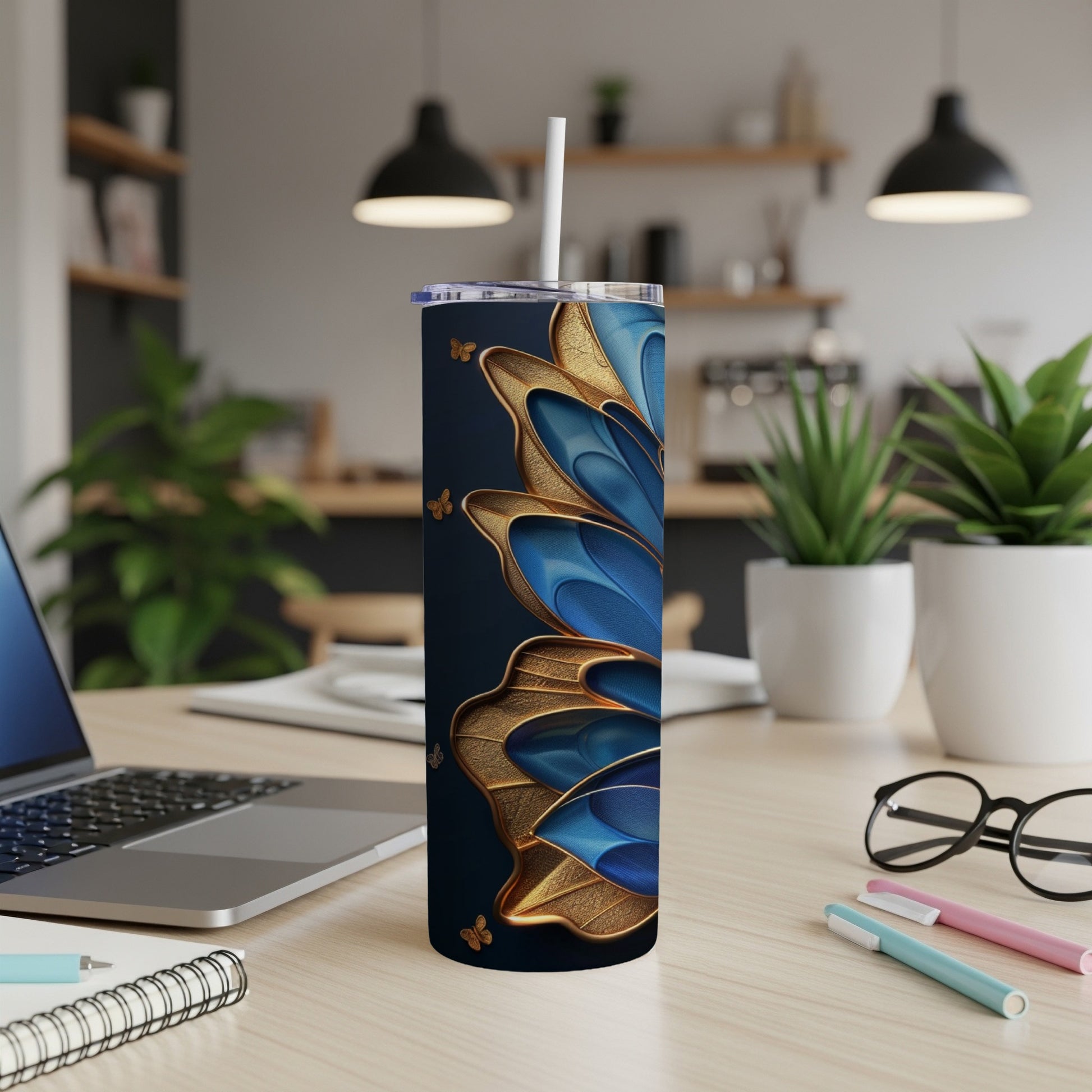 Blue and gold butterfly tumbler with straw on a desk.