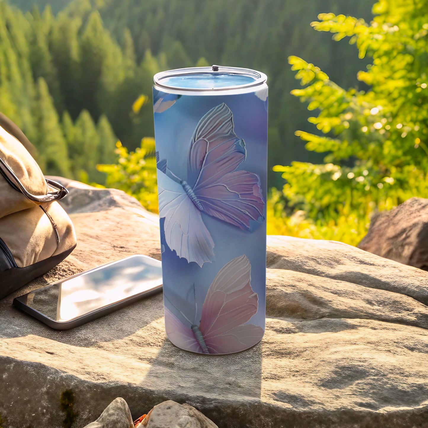 Blue and pink butterfly pattern on a white tumbler with phone and backpack outdoors.