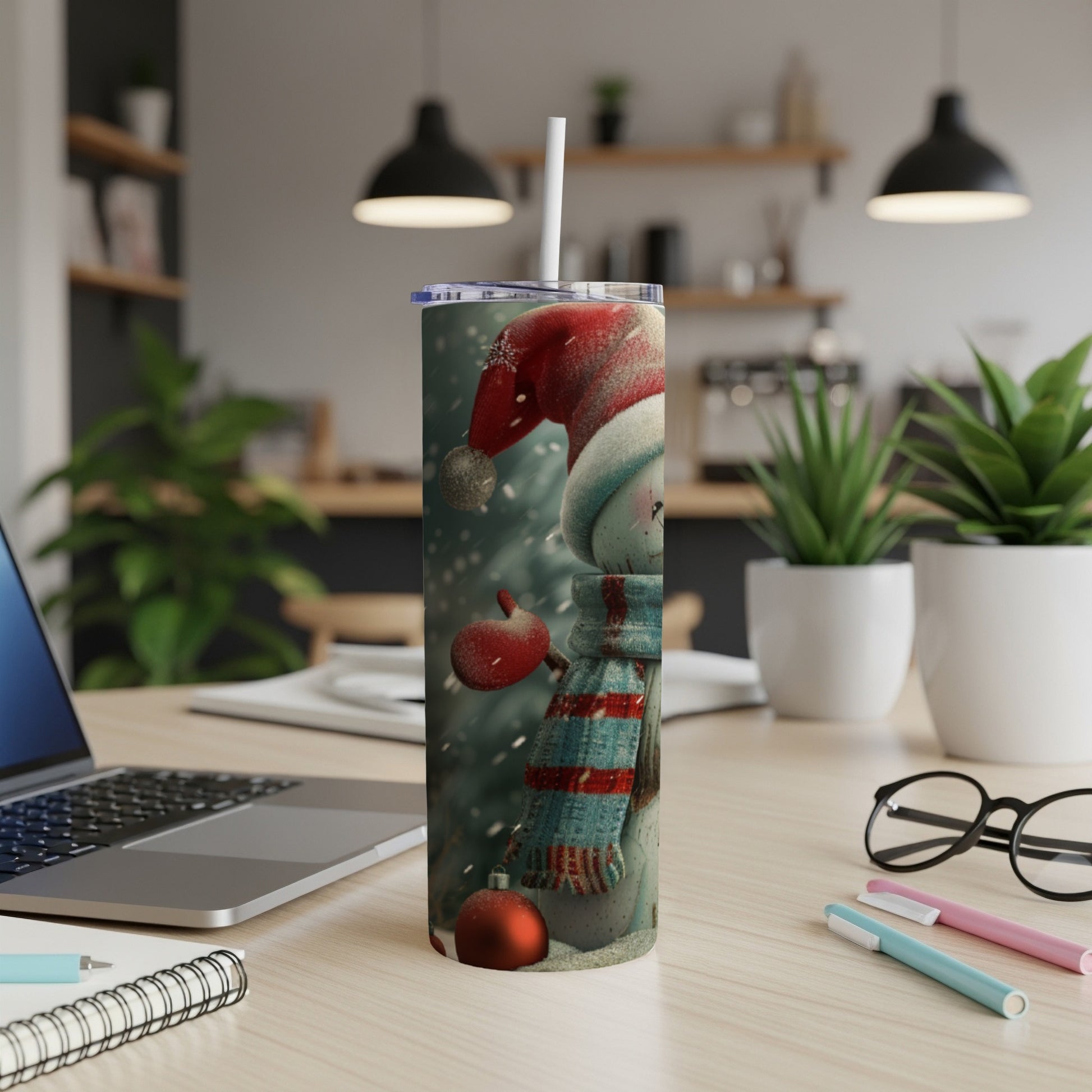 Snowman tumbler with red hat and scarf, on a desk.