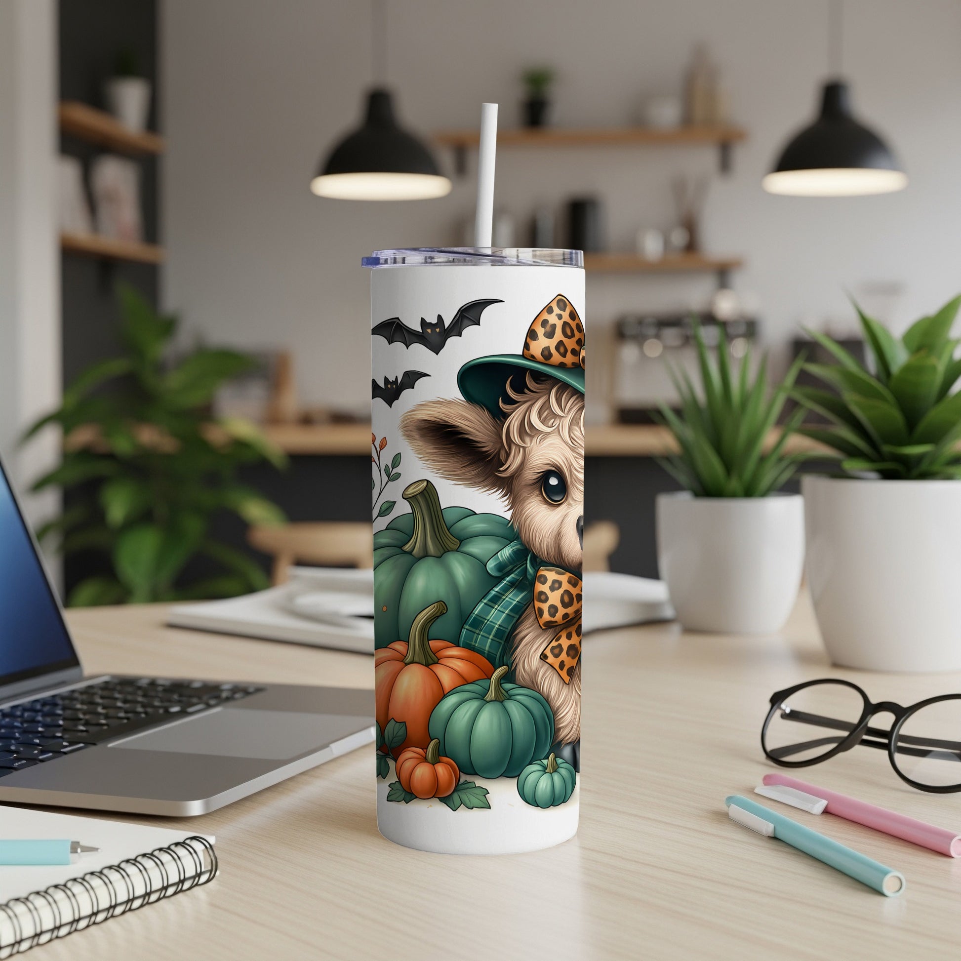Cow with witch hat and pumpkins on a tumbler with bats, surrounded by office items.