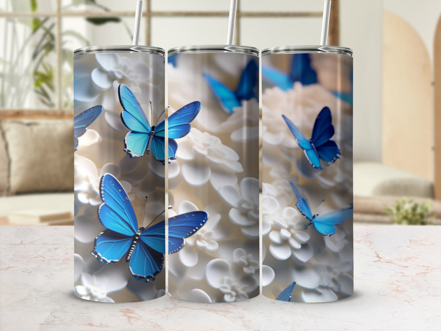 Three tumblers with blue butterflies and white flowers on a marbled surface.