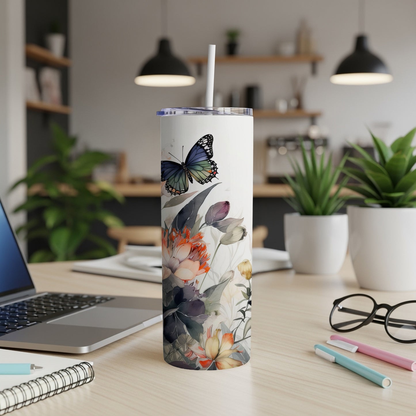 White tumbler with floral and butterfly design on a desk.