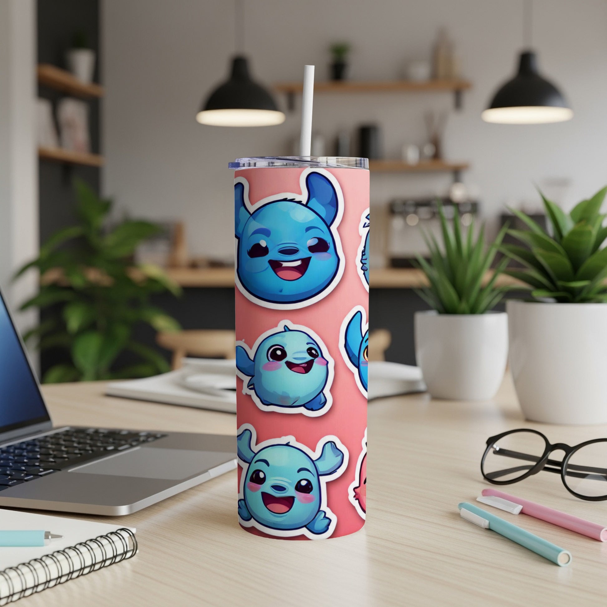 Pink tumbler with cartoon monster stickers on a desk.