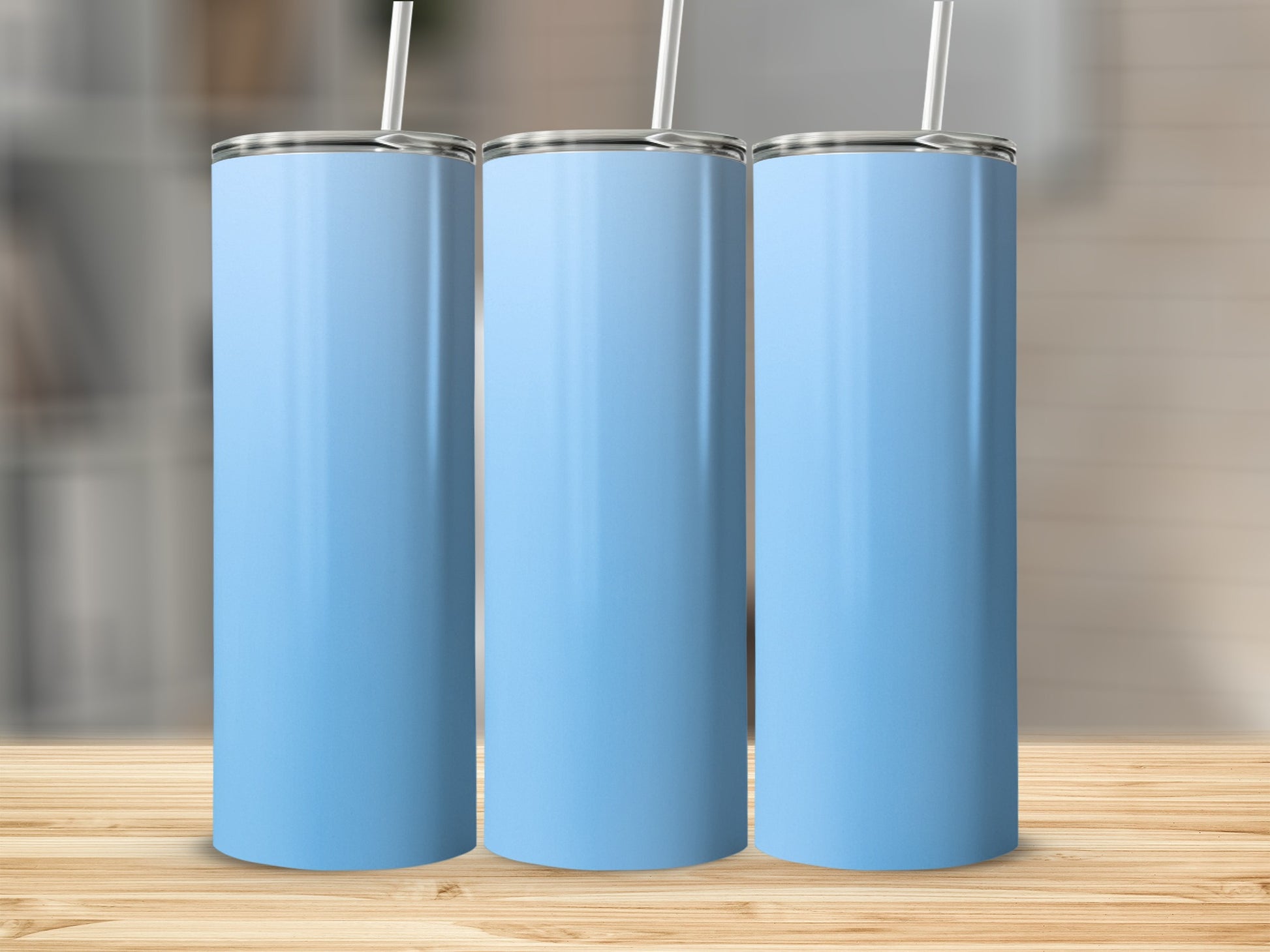 Three light blue tumblers with straws on a wooden surface.