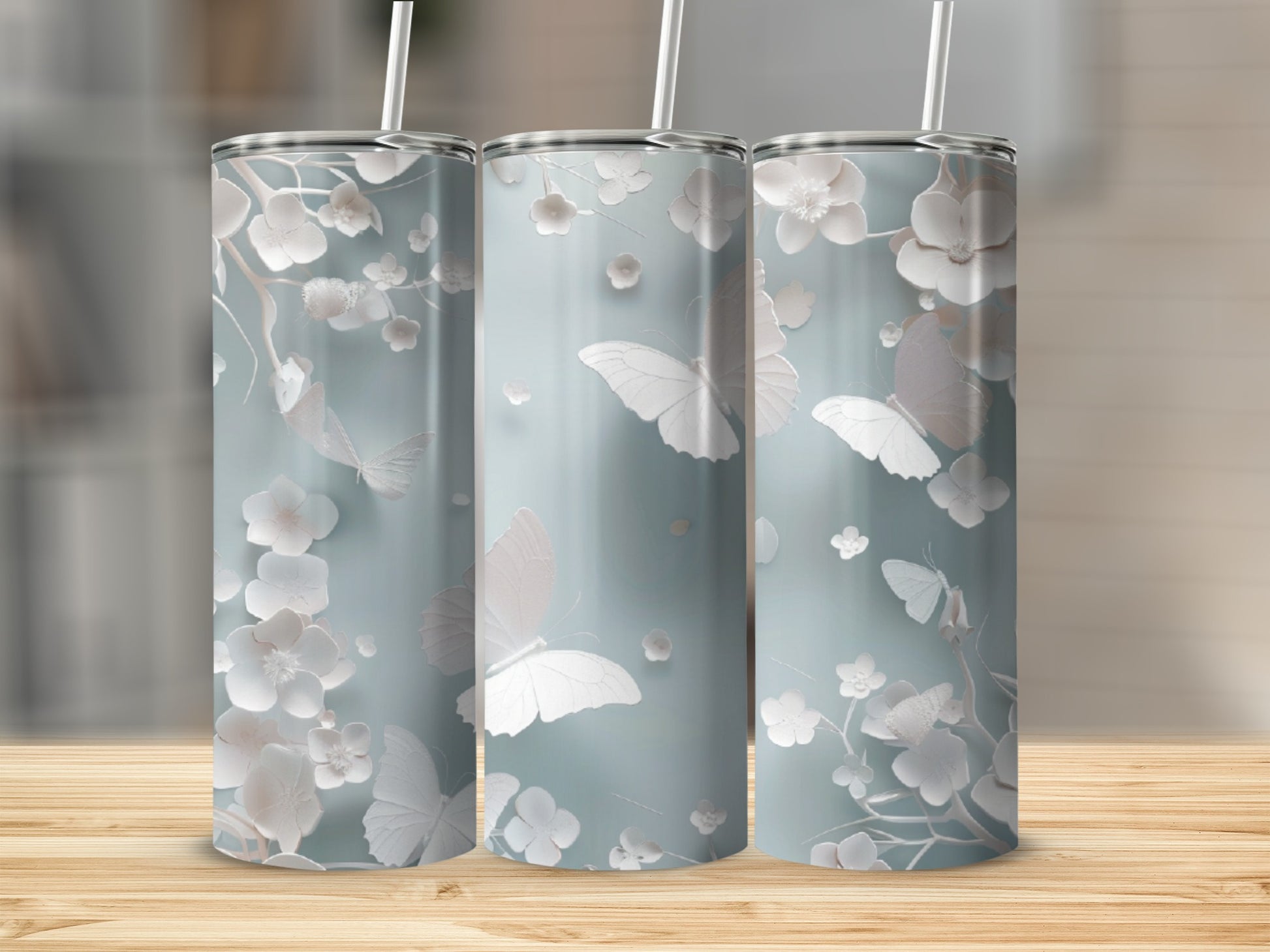Three light blue tumblers with white floral and butterfly designs.