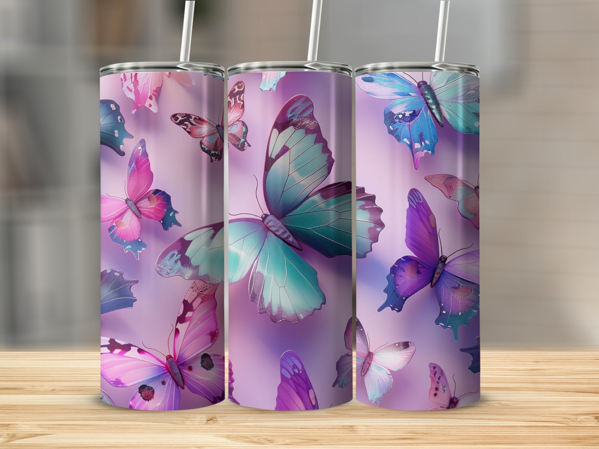 Three tumblers with colorful butterfly designs on a wooden surface.