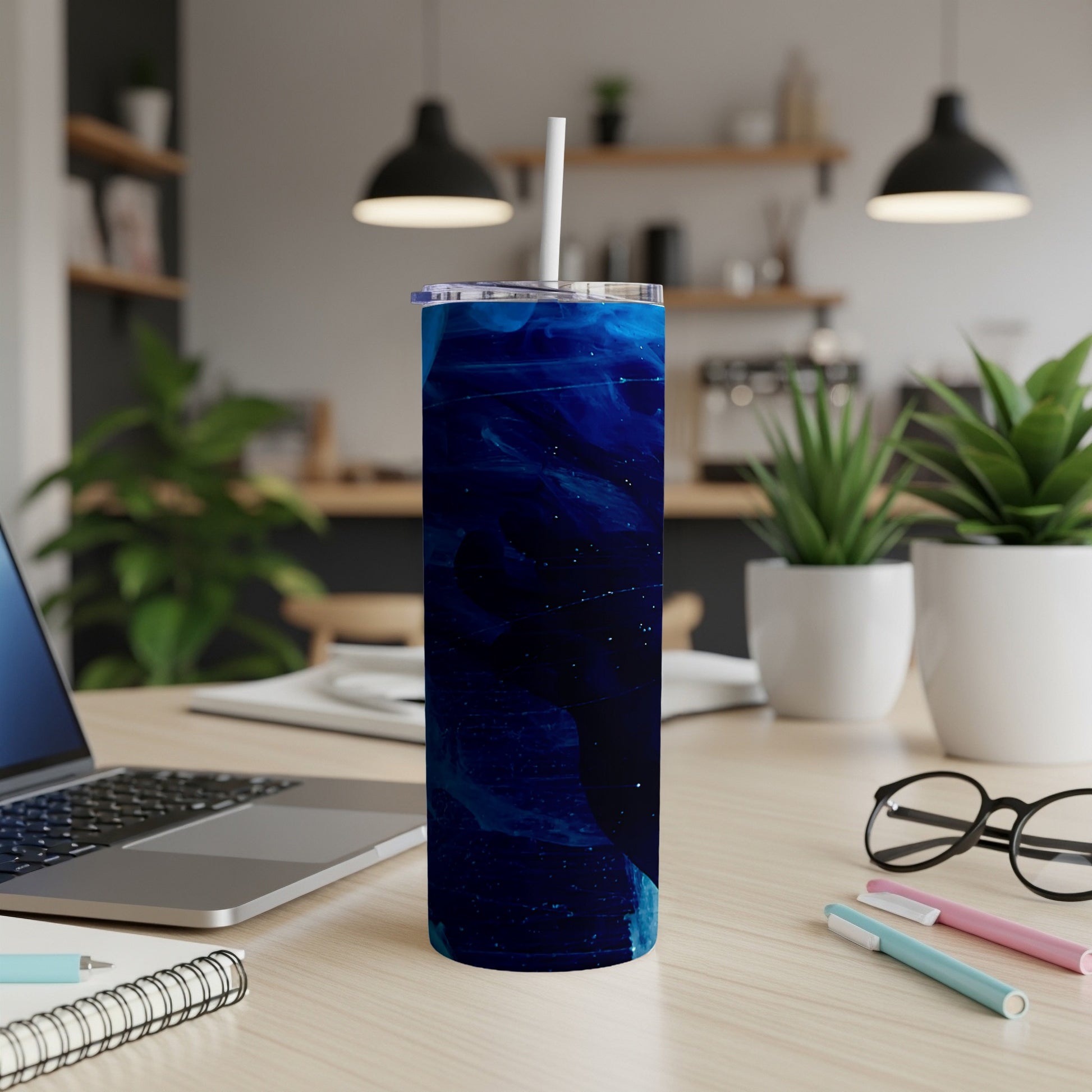 Blue abstract pattern skinny tumbler with straw on desk.