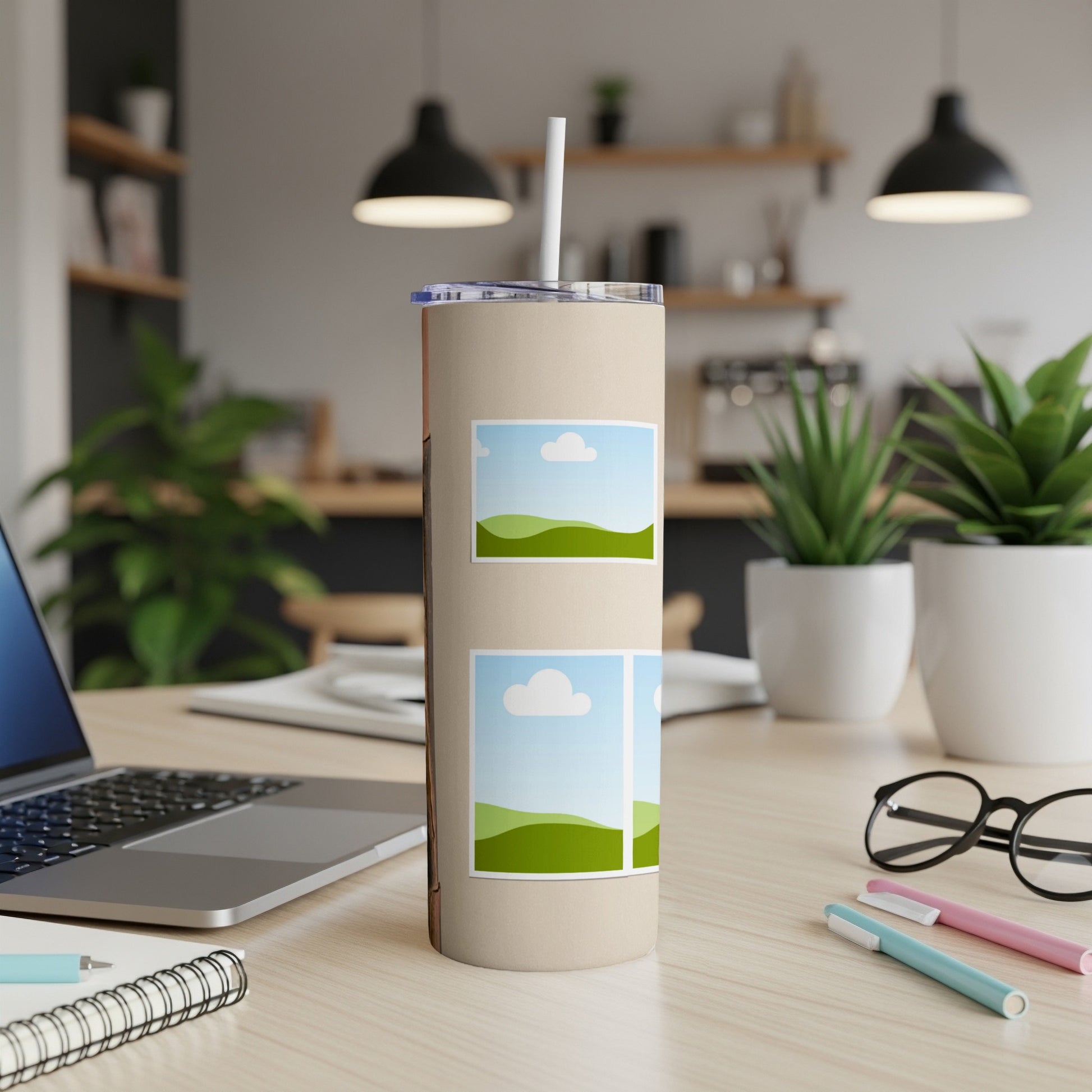 Tan tumbler with two scenic landscape images and a straw on a wooden desk.