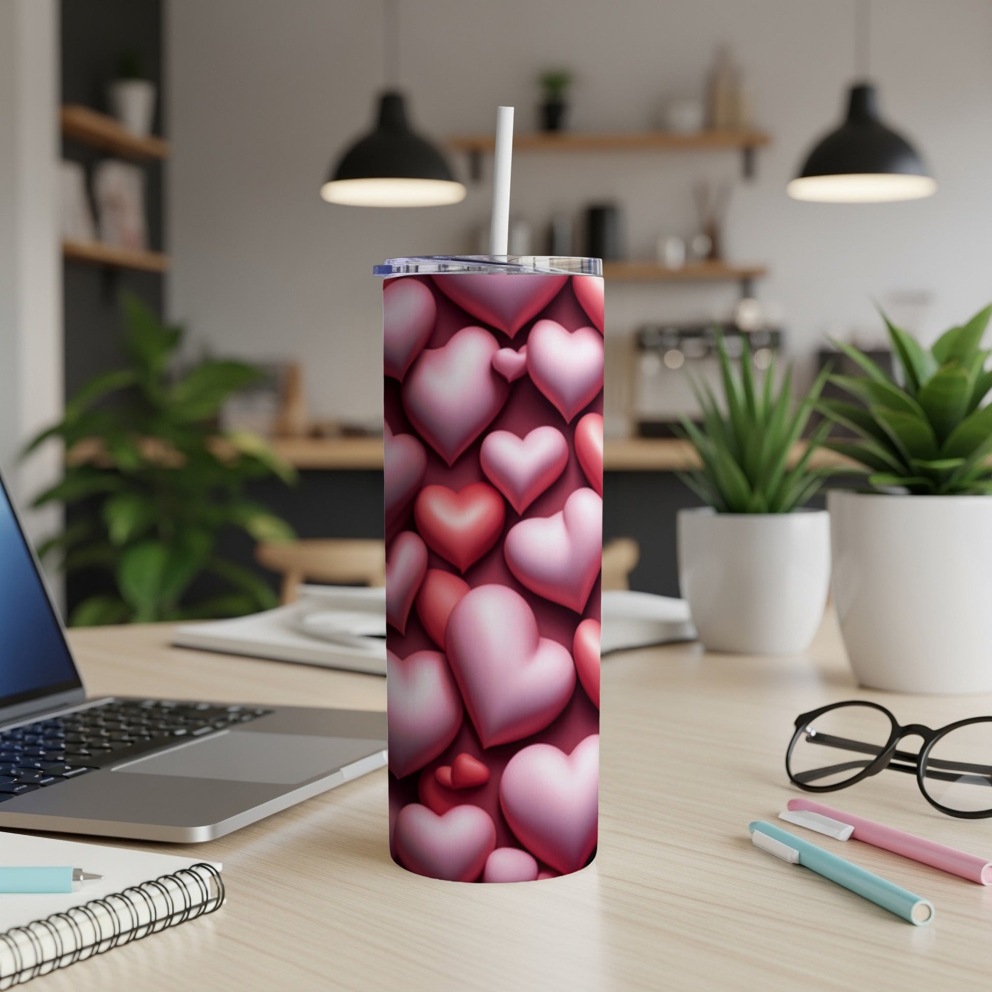Pink and red heart pattern on a stainless steel tumbler with a straw.