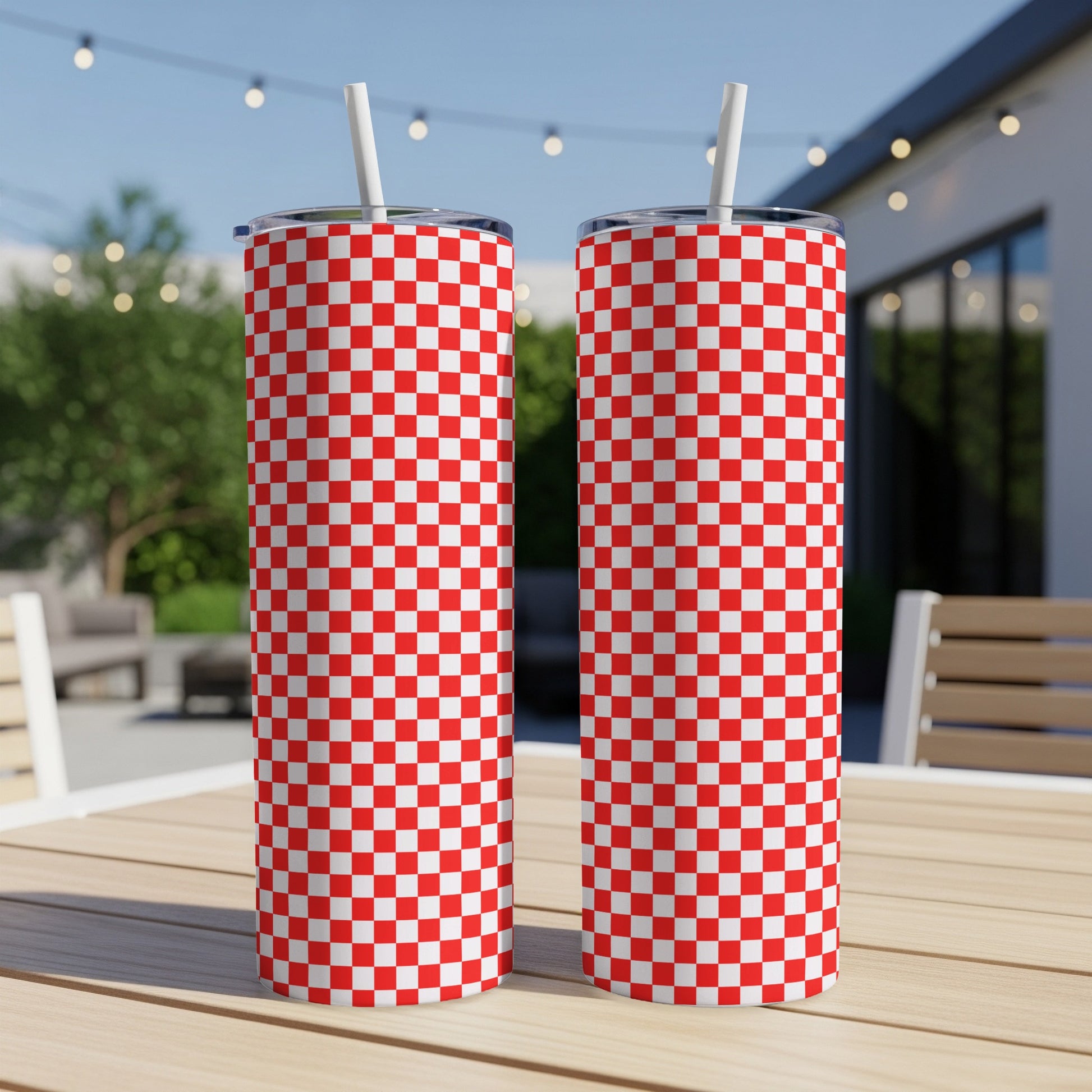 Two red and white checkered tumblers with straws on a wooden table.