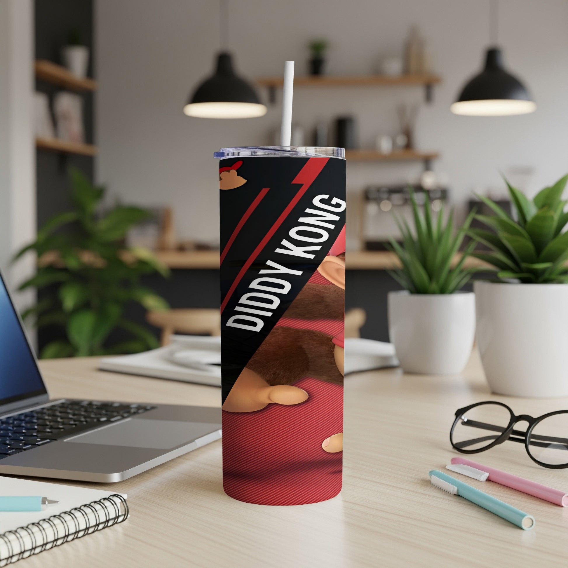 Diddy Kong red tumbler with straw on a desk with a laptop.