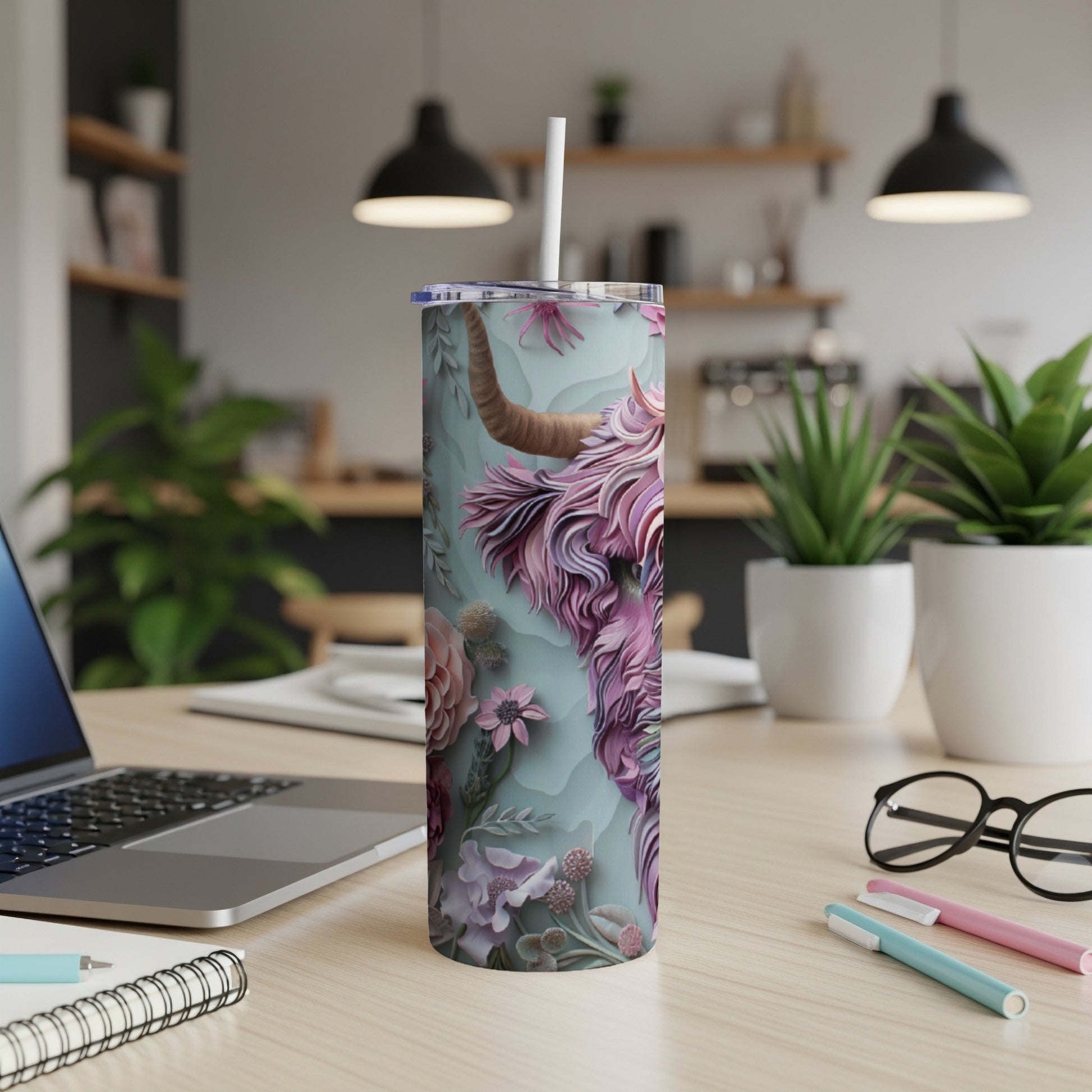 Tall tumbler with a Highland cow and floral design, on a desk.