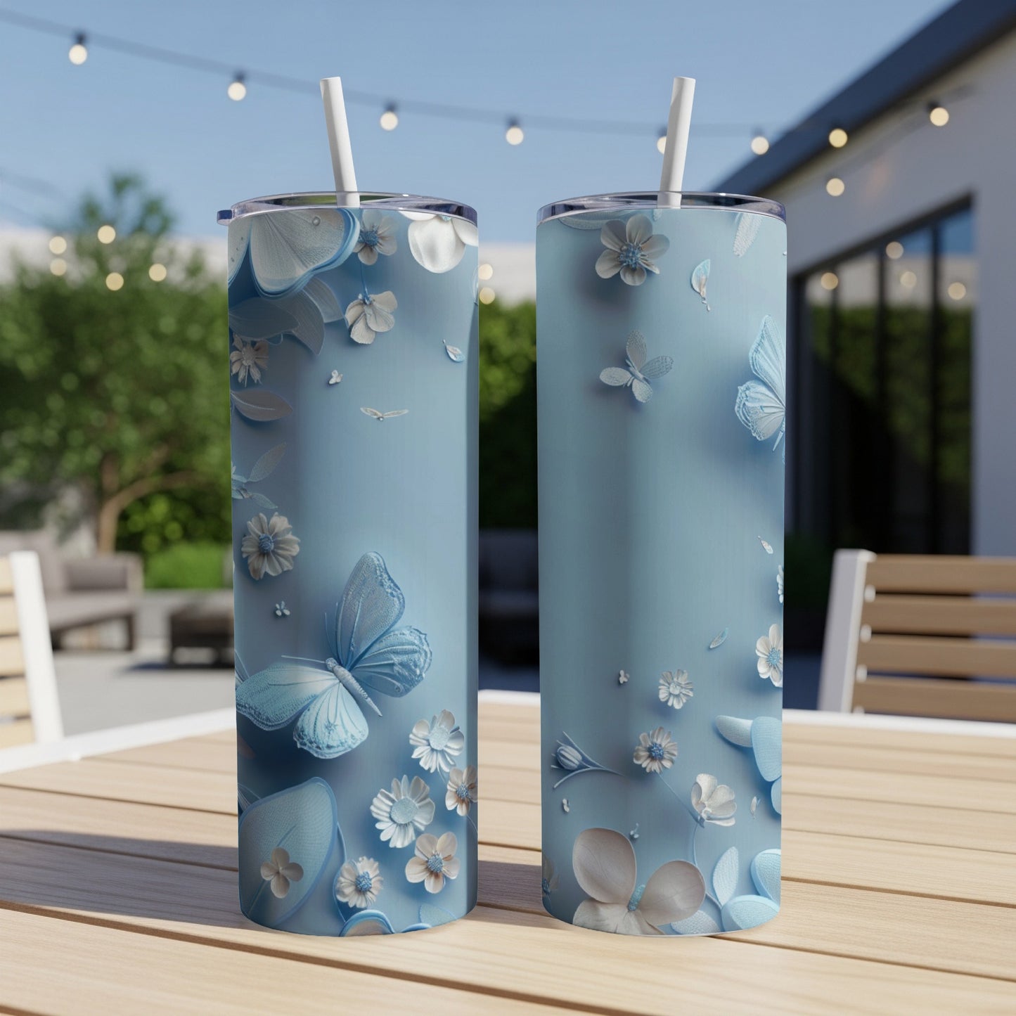 Two light blue tumblers with floral and butterfly designs sit on a wooden table.
