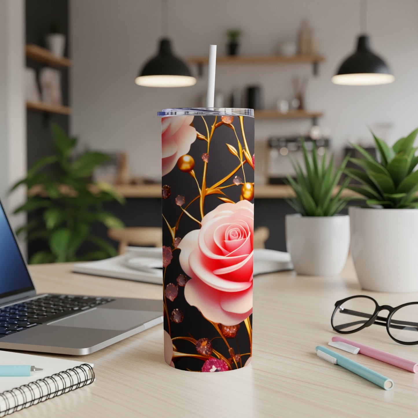 Pink rose tumbler with straw on a desk, with laptop and plants.