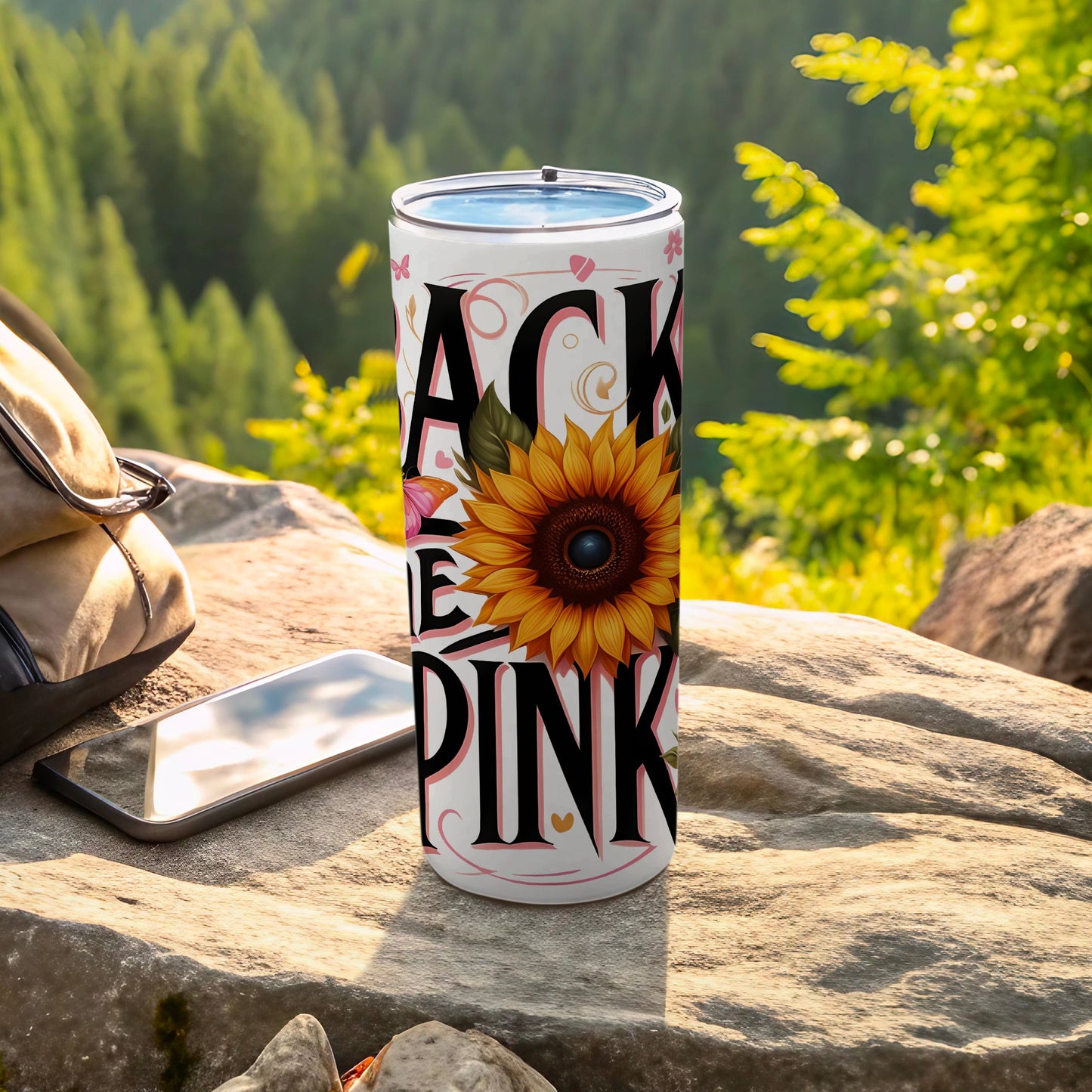 Blackpink tumbler with sunflower graphic on a rocky outdoor surface.