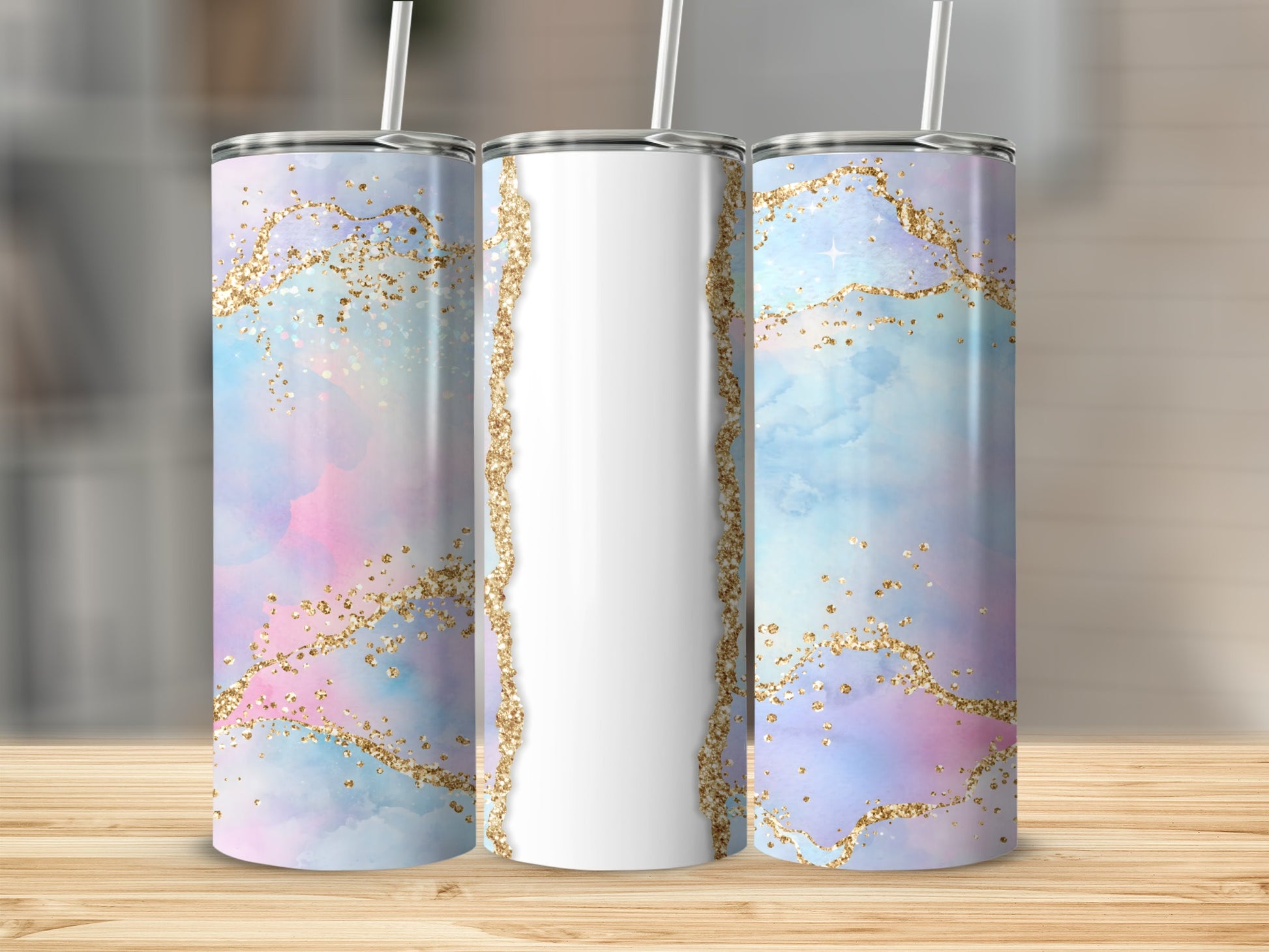 Three tumblers with pastel watercolor and gold glitter designs on a wooden surface.