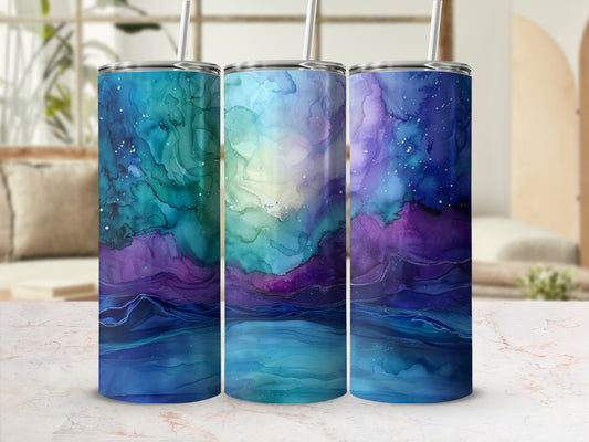 Three tumblers with swirling blue, green, and purple galaxy art and straws.