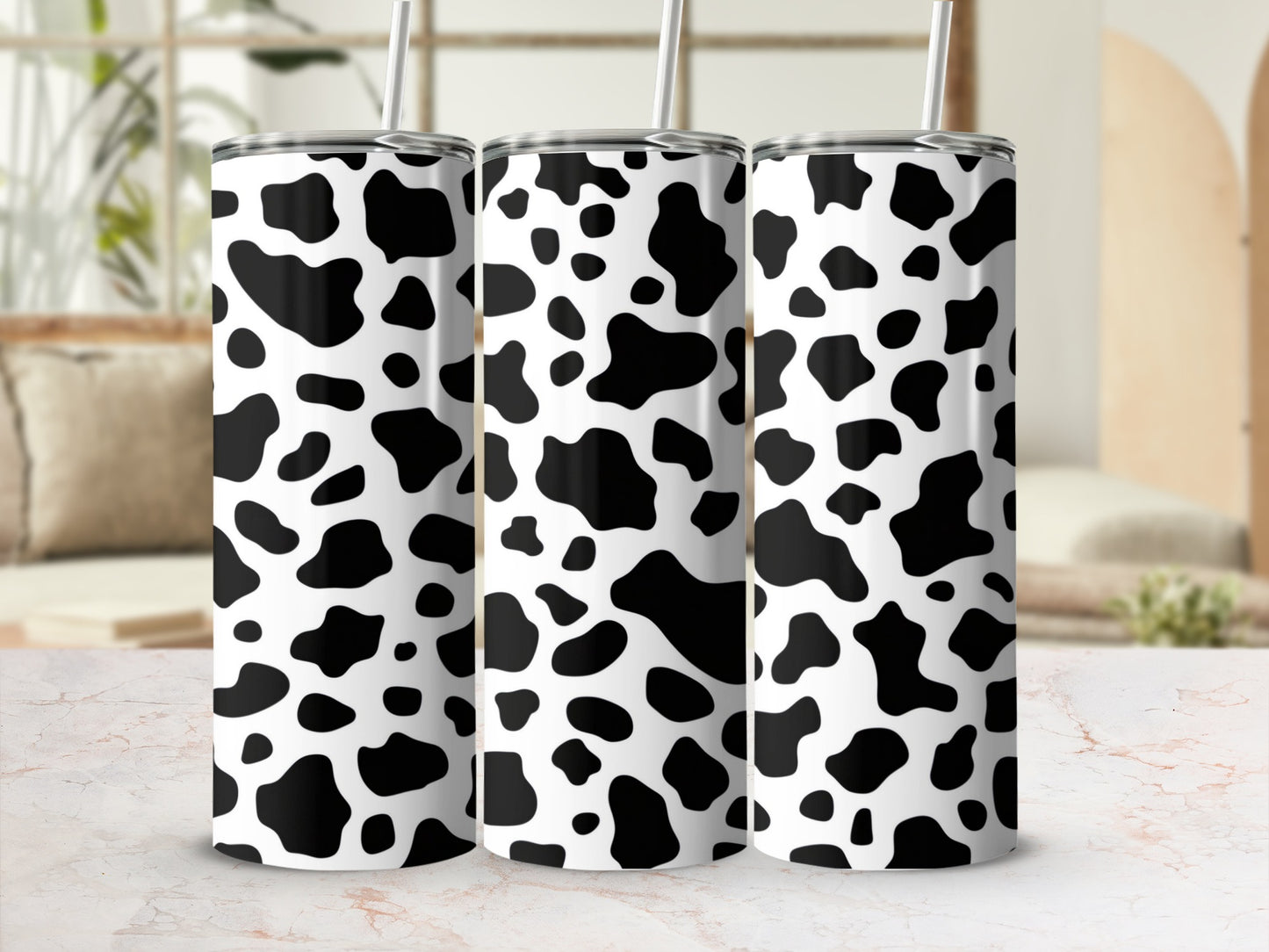Three white tumblers with black cow print pattern and straws.