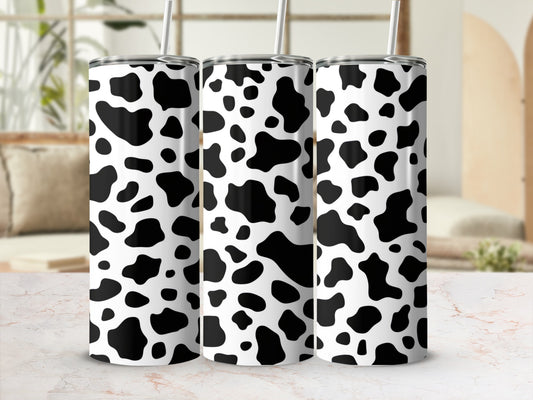 Three white tumblers with black cow print pattern and straws.