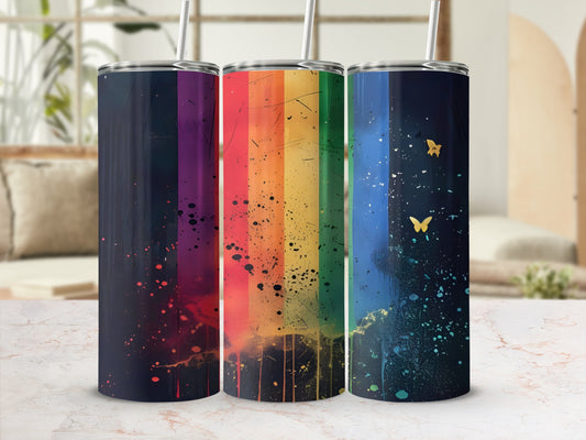 Three tumblers with rainbow and butterfly designs against a blurred background.