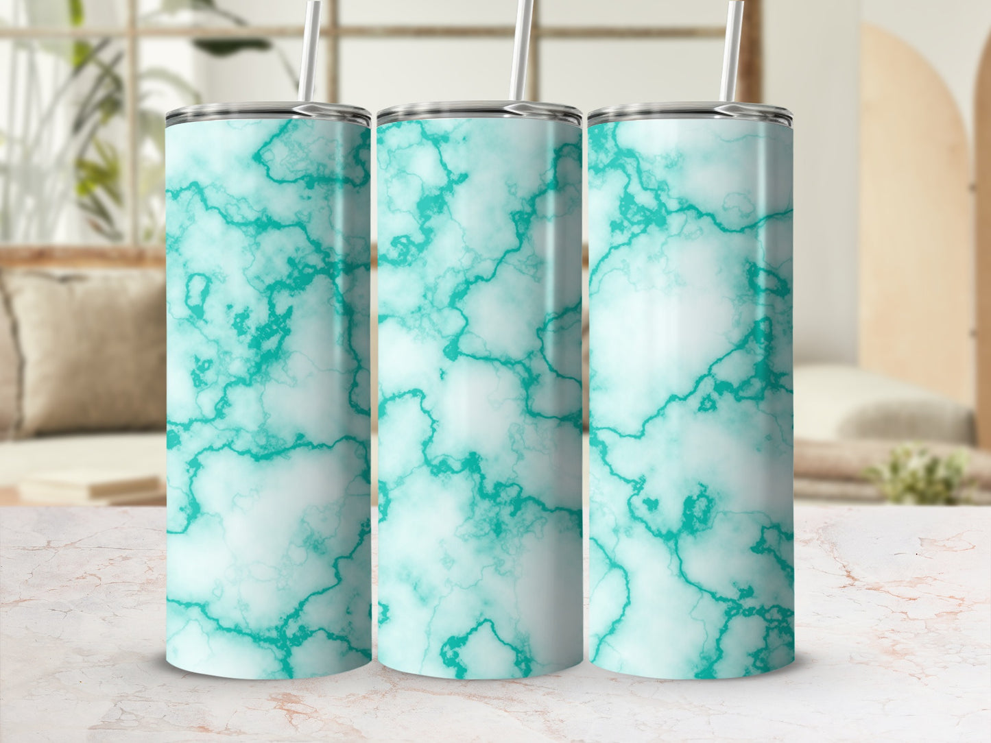 Three teal marble pattern tumblers with straws on a patterned surface.