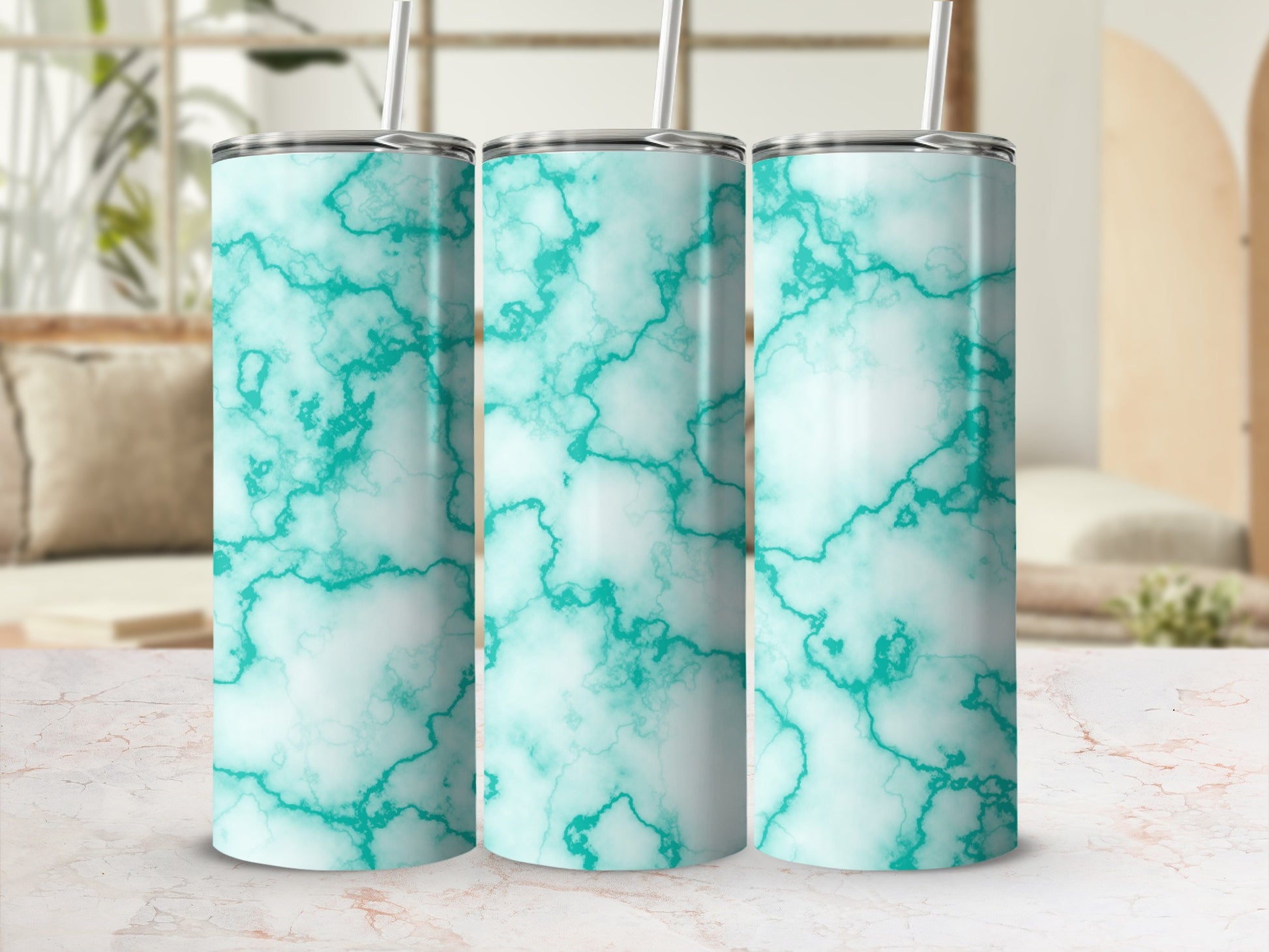 Three teal marble pattern tumblers with straws on a patterned surface.