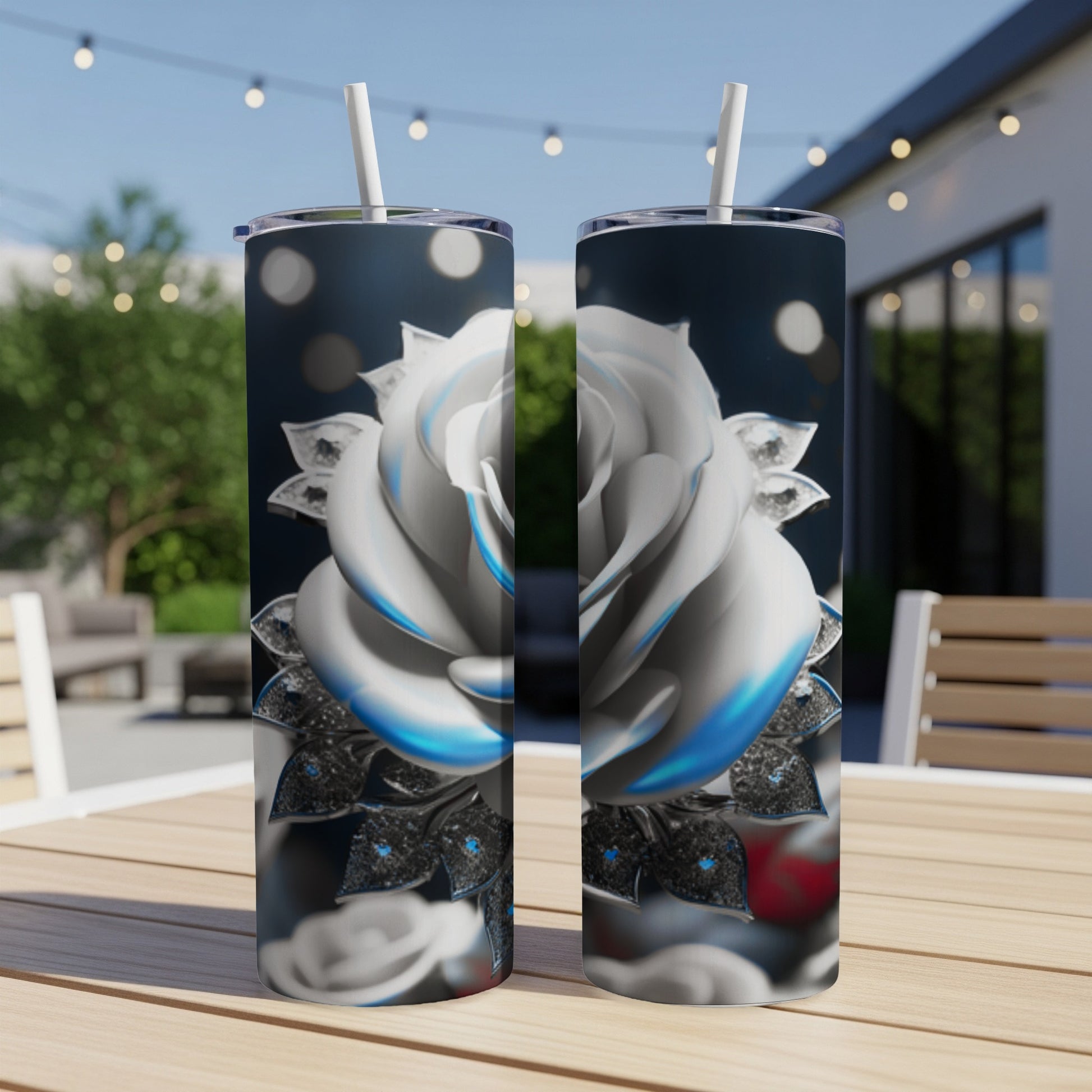 White rose design on two slim tumblers with straws on a table.