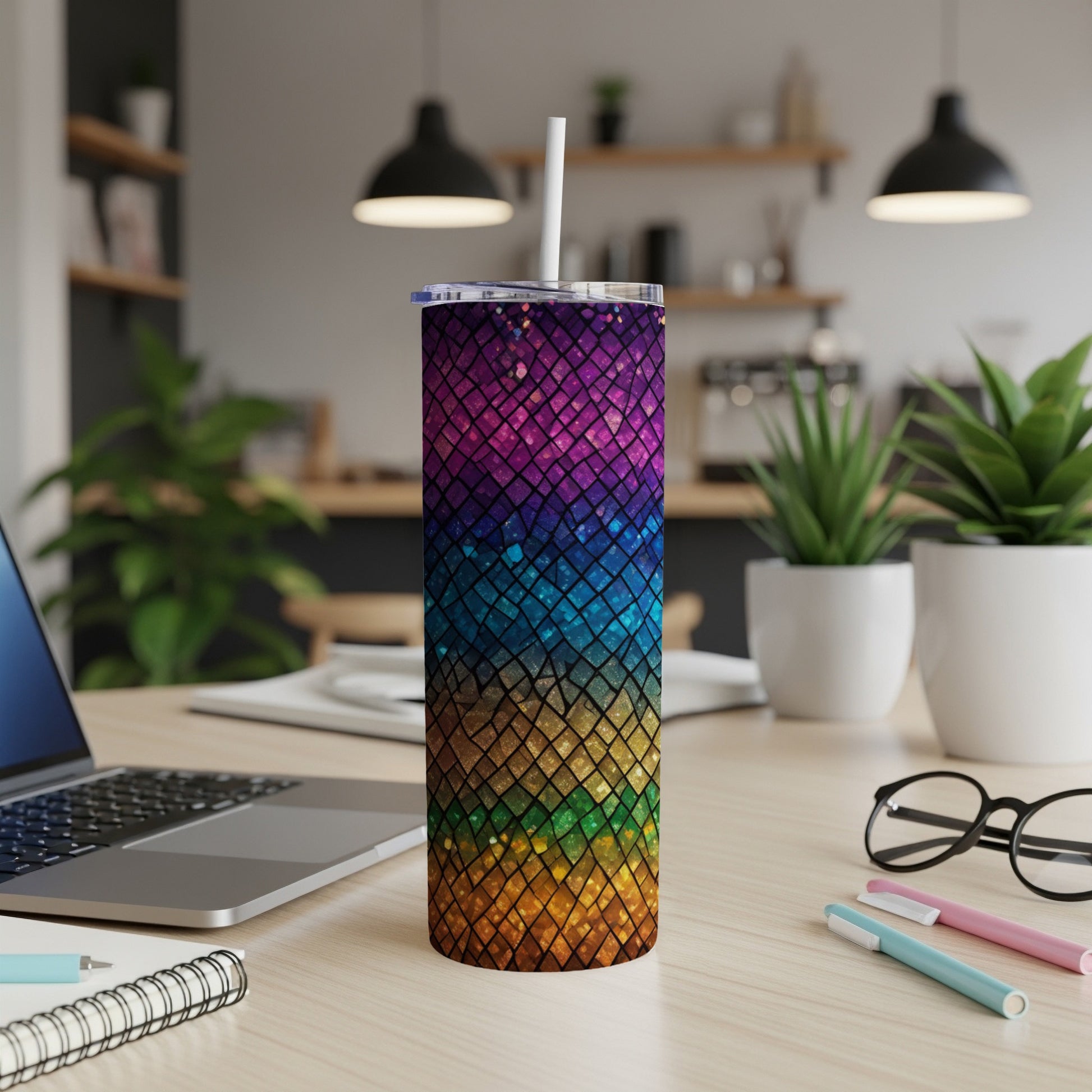 Rainbow glitter tumbler with straw on a desk with laptop and pens.