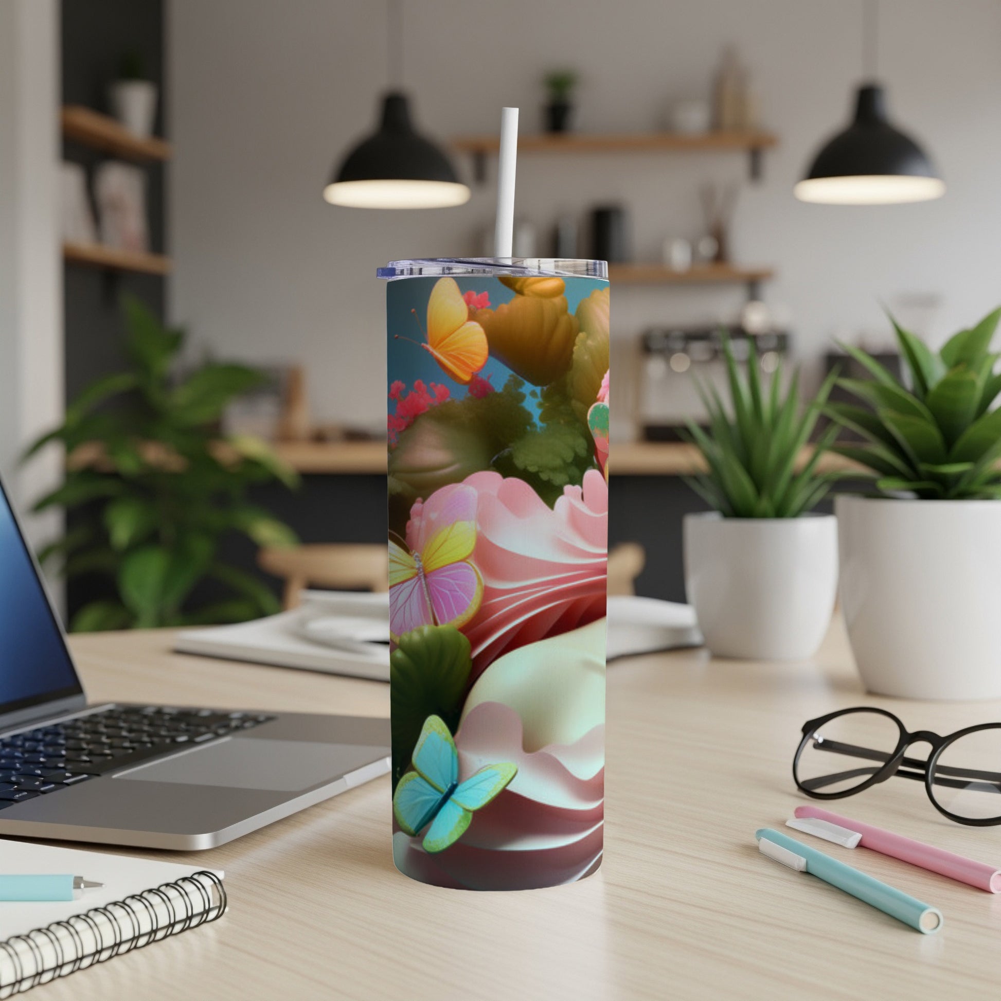 Tall tumbler with butterflies and pink floral design on desk.