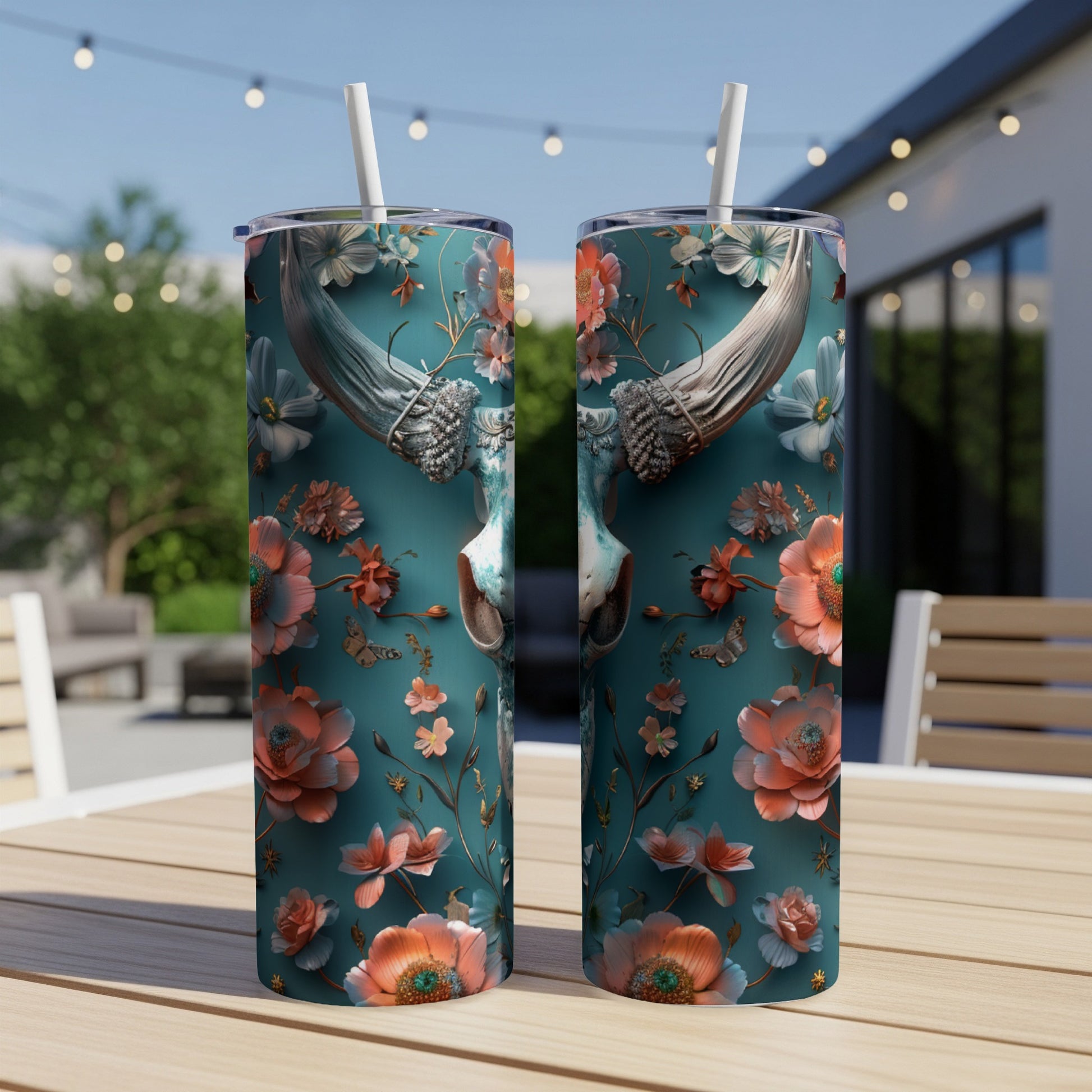 Two teal tumblers with floral and butterfly designs sit on a wooden table.