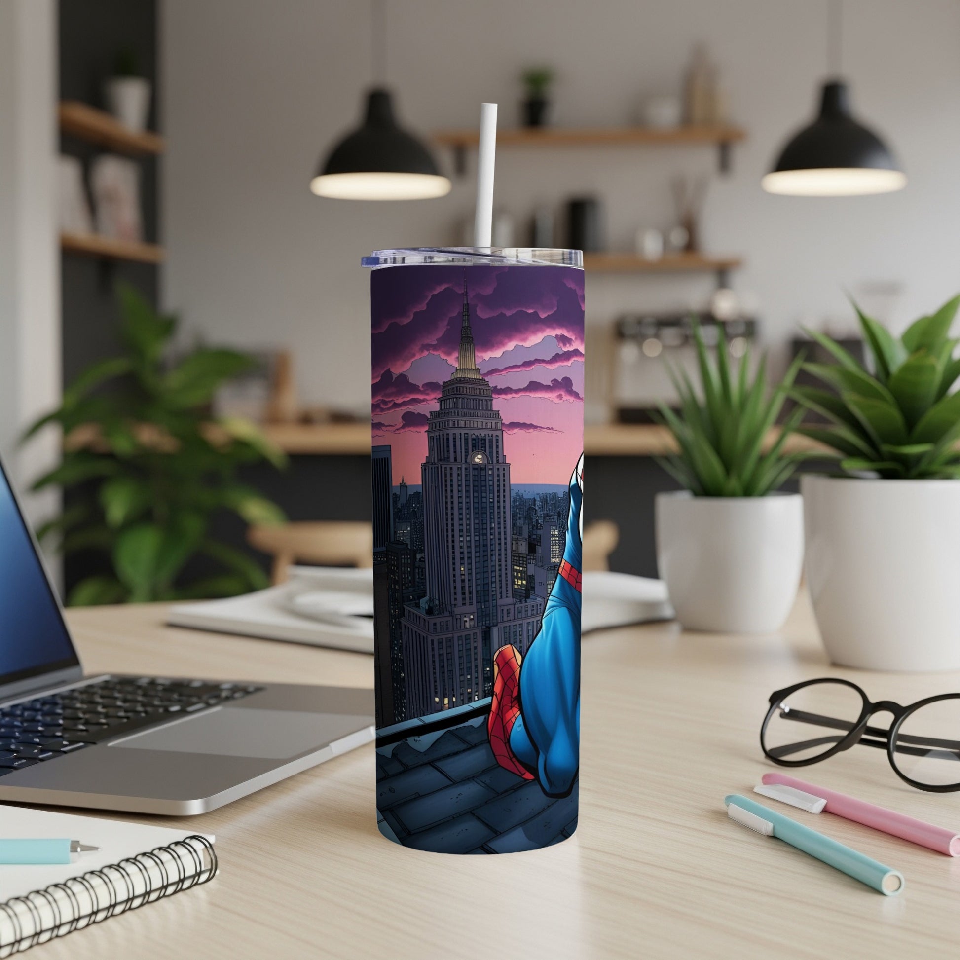 Superhero tumbler with cityscape and sunset background on a desk.