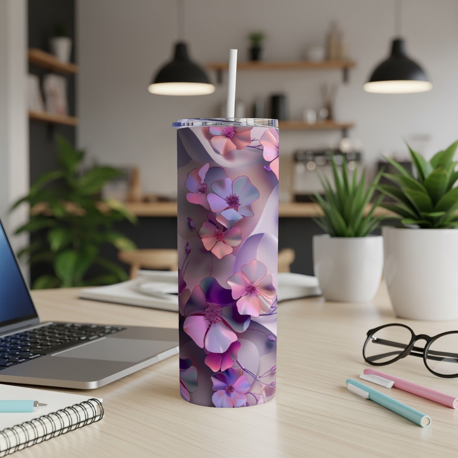 Pink and purple floral tumbler with straw on a desk.