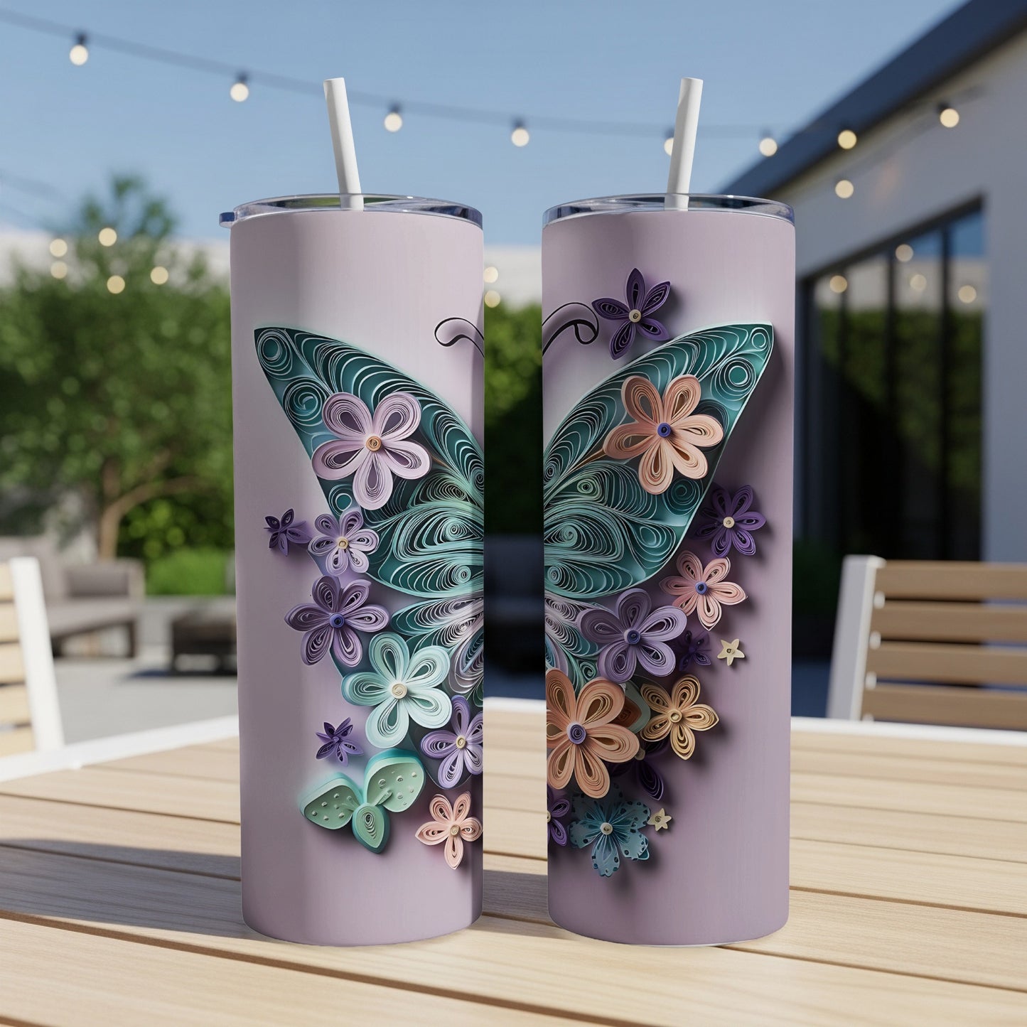 Two tumblers with a quilled butterfly and floral design on a wooden table.