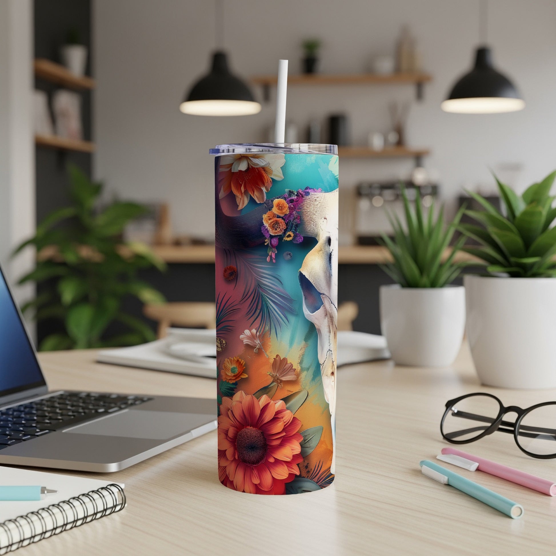 Floral skull tumbler with straw on a desk.