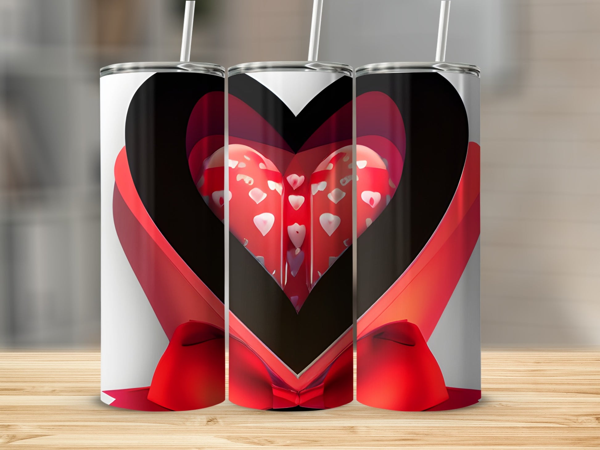 Three tumblers with heart designs and red ribbon, on a wooden surface.